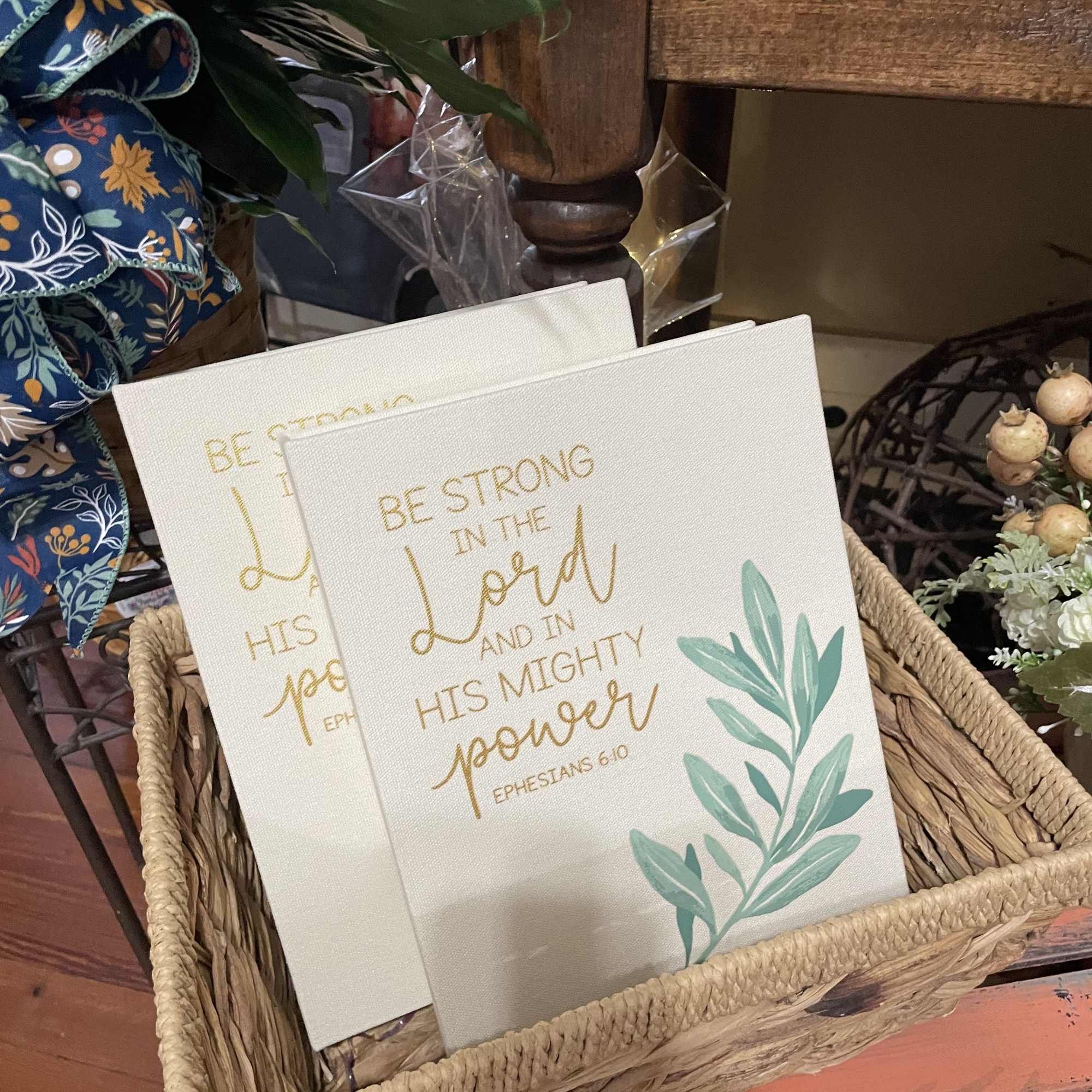 Two decorative canvas signs in a woven basket with gold lettering