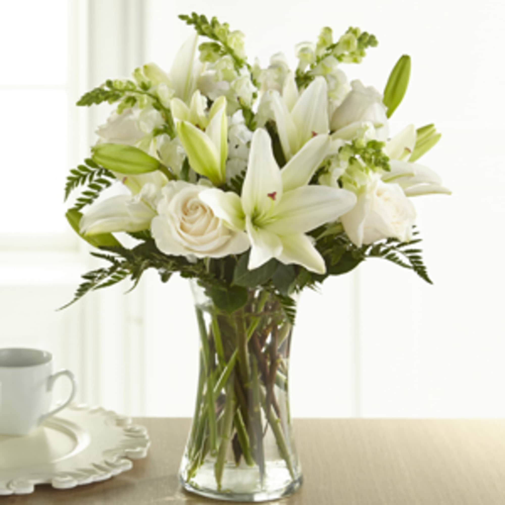 White lilies and roses arranged in a clear glass vase