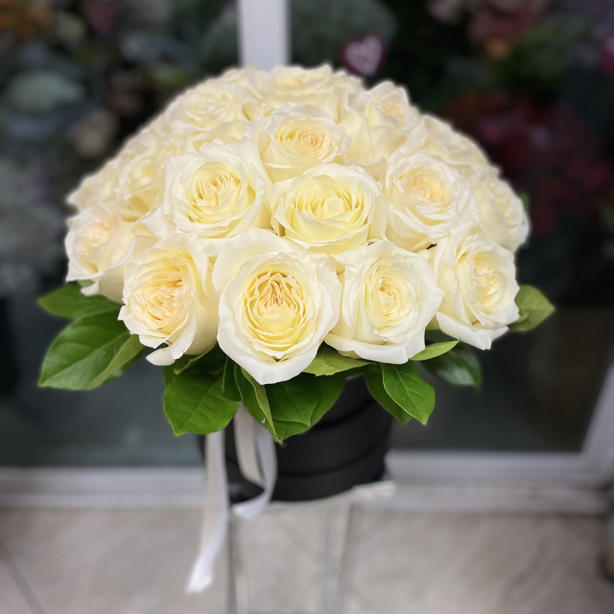 Bouquet of cream white roses in a black box with a white ribbon