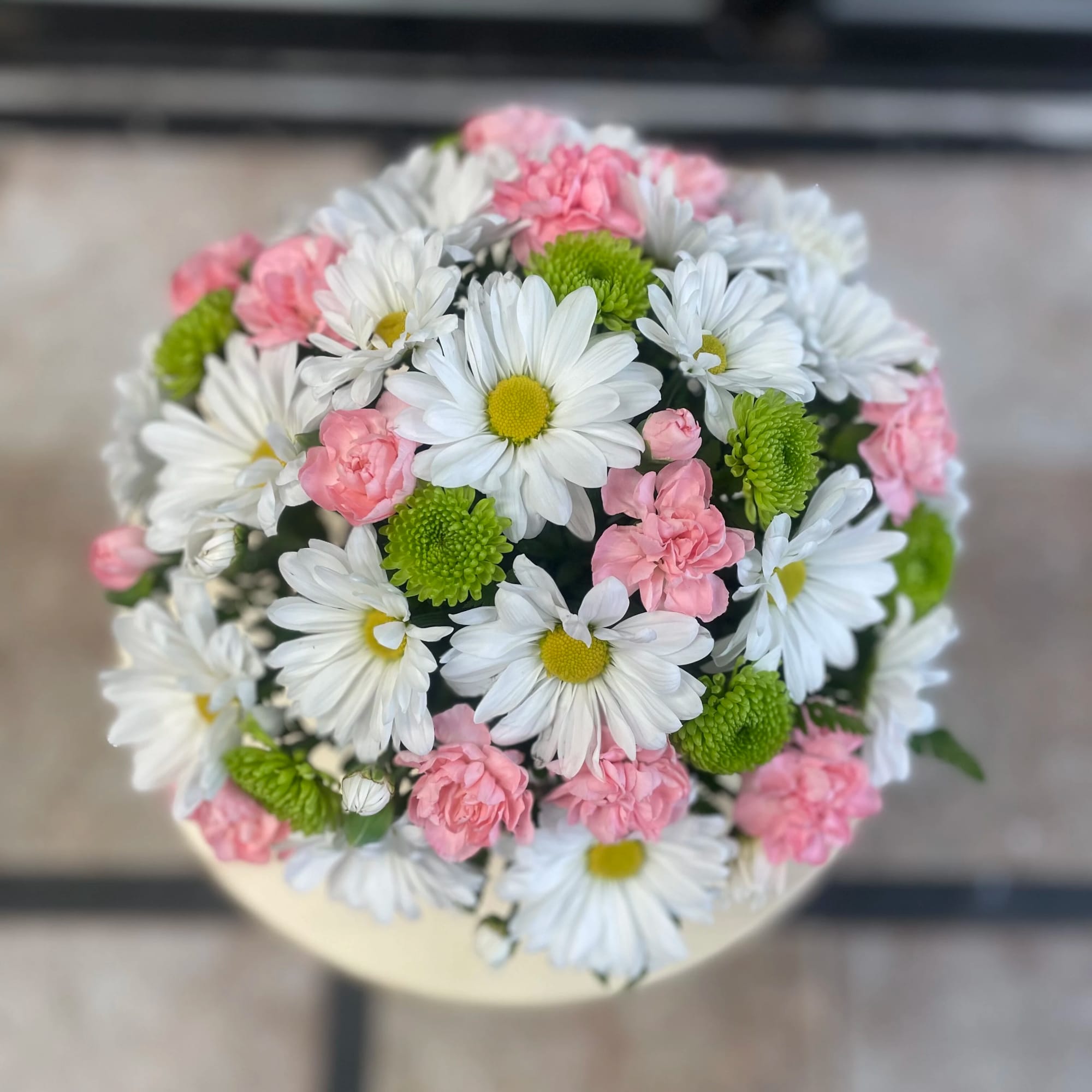 Round bouquet of white daisies, pink carnations, and green button mums