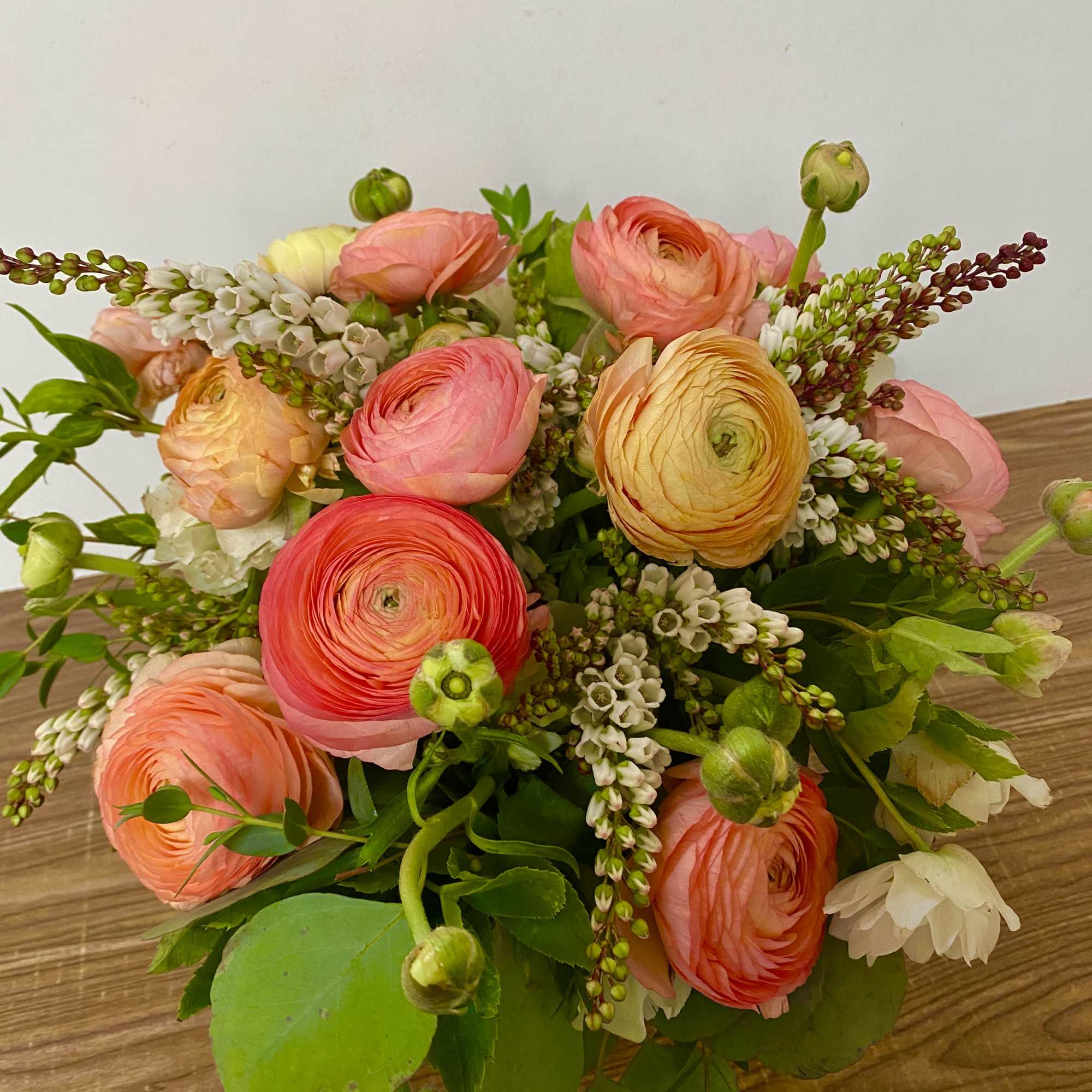 Bouquet of pink, peach, and yellow ranunculus with white filler flowers