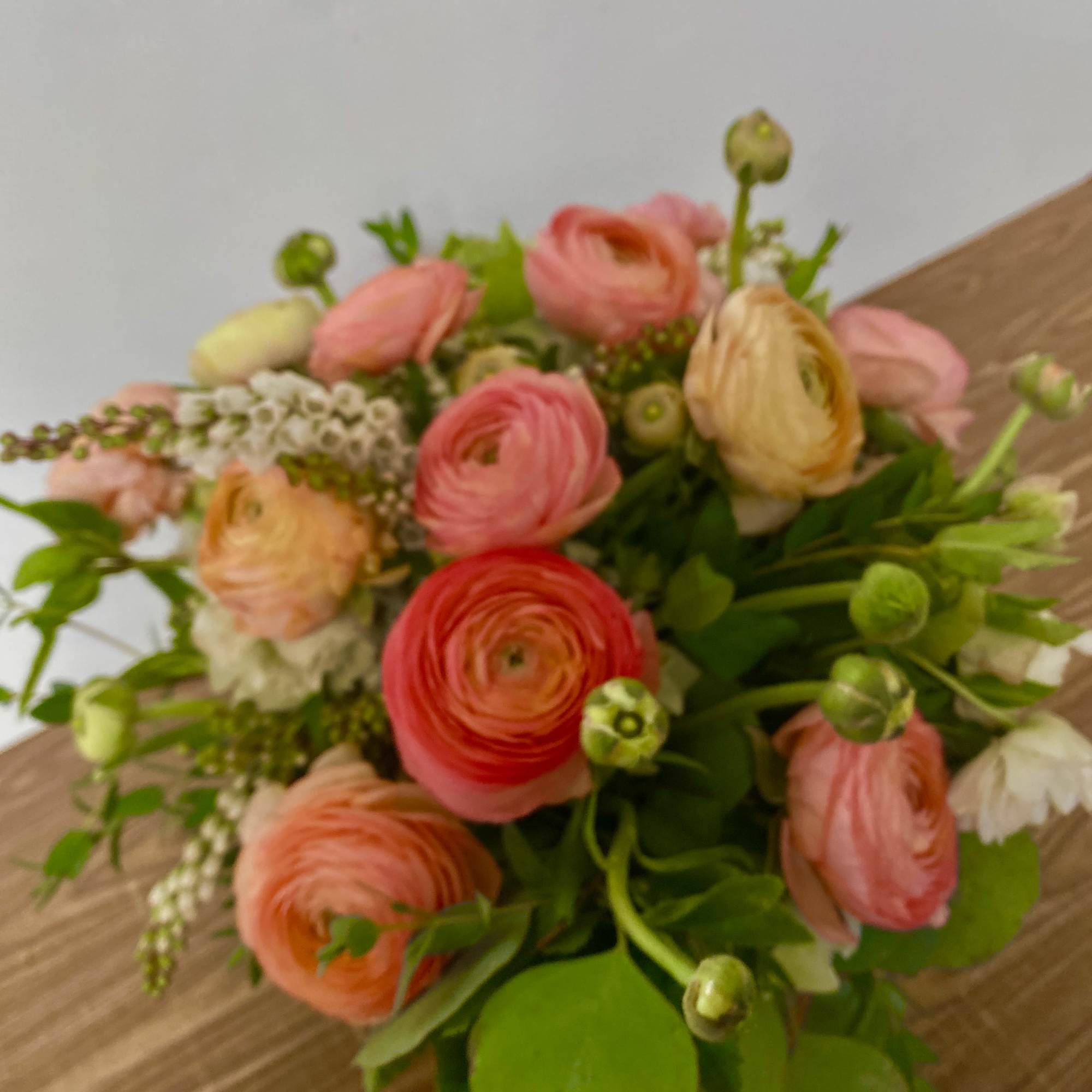 Bouquet of pink and peach ranunculus with green foliage
