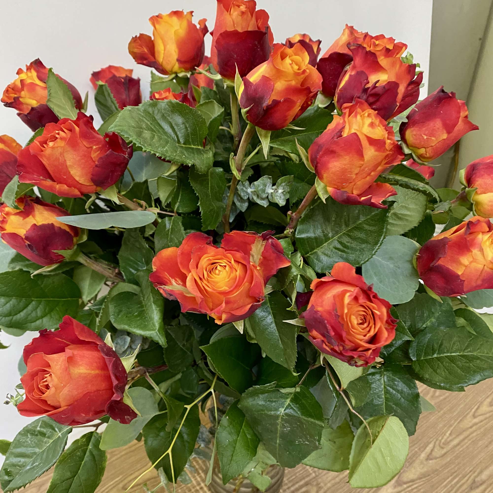 2 Dozen hot orange roses in a glass vase with a nice