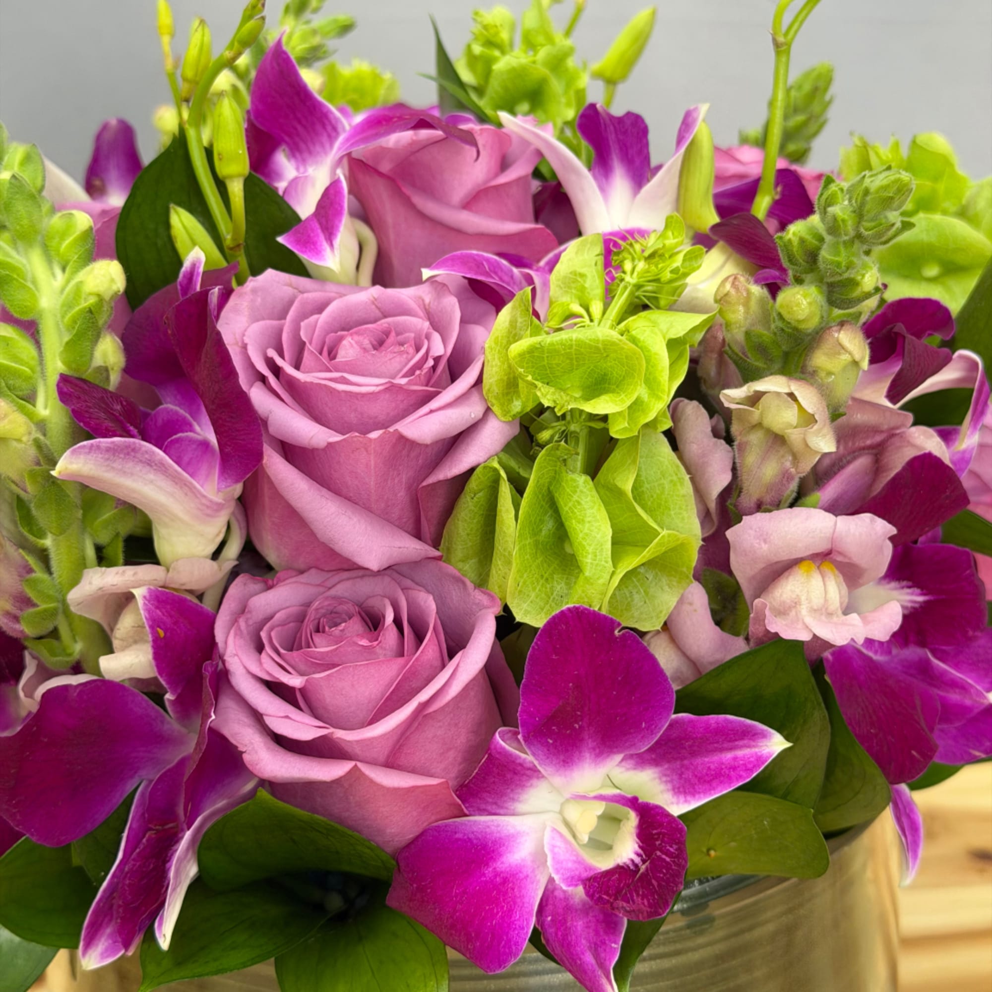 Lavender roses and purple orchids in a metal container