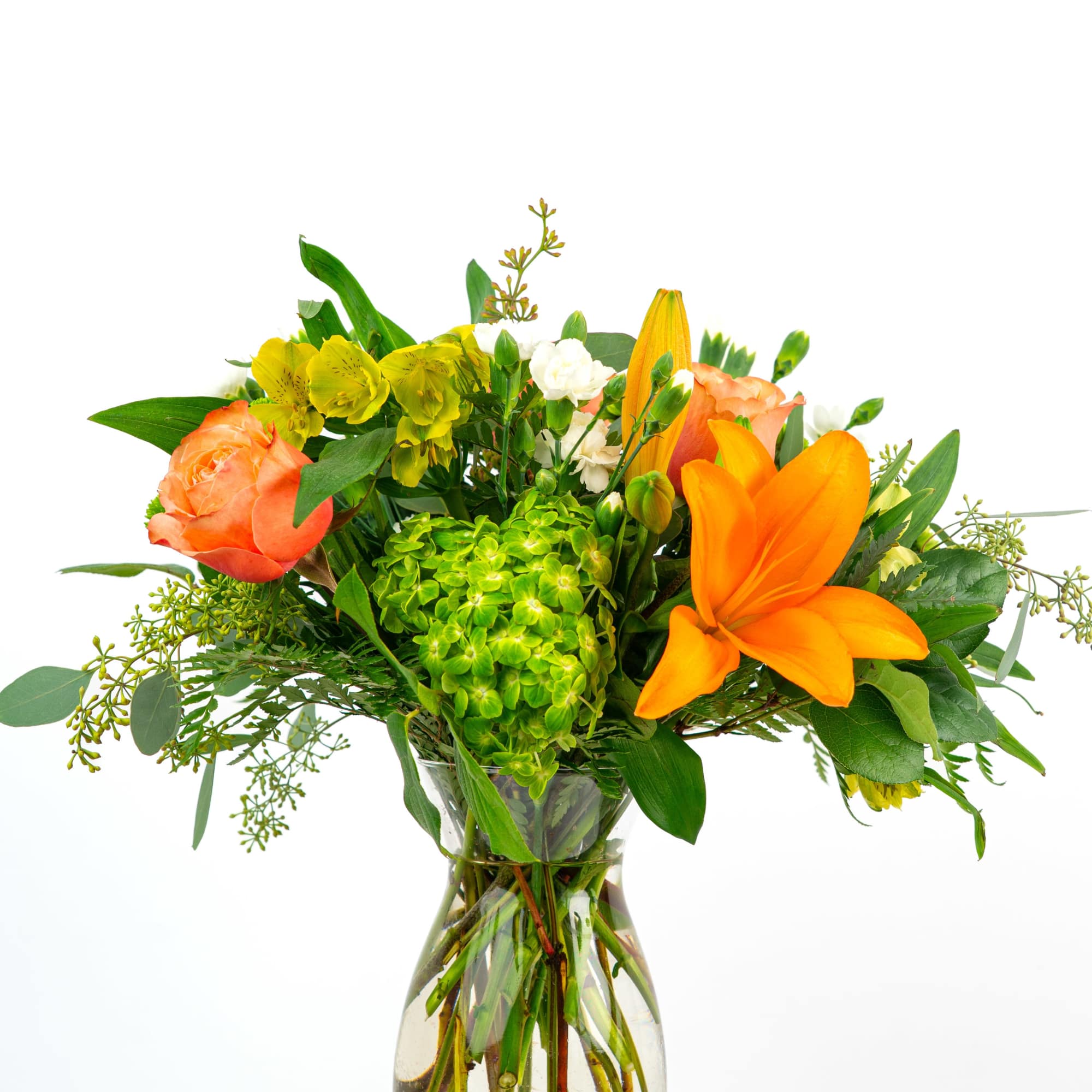 Mixed bouquet of orange lilies, peach roses, green hydrangea, and yellow blooms in a clear glass vase