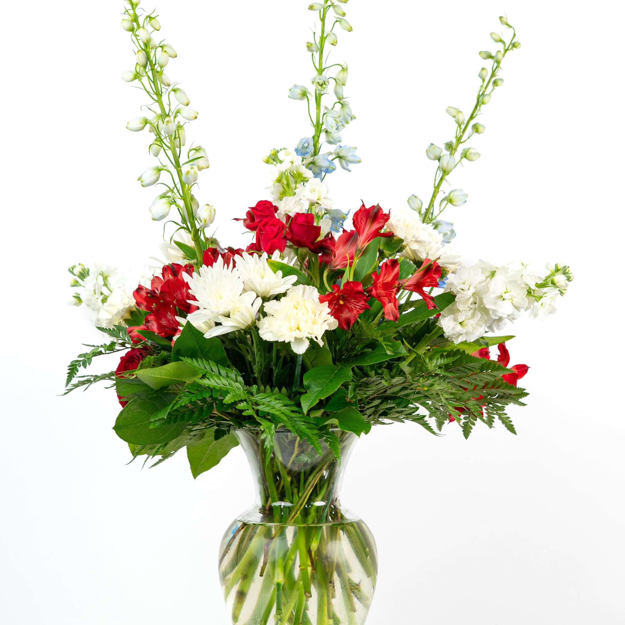 Tall red, white, and blue mixed flower arrangement in a clear glass vase