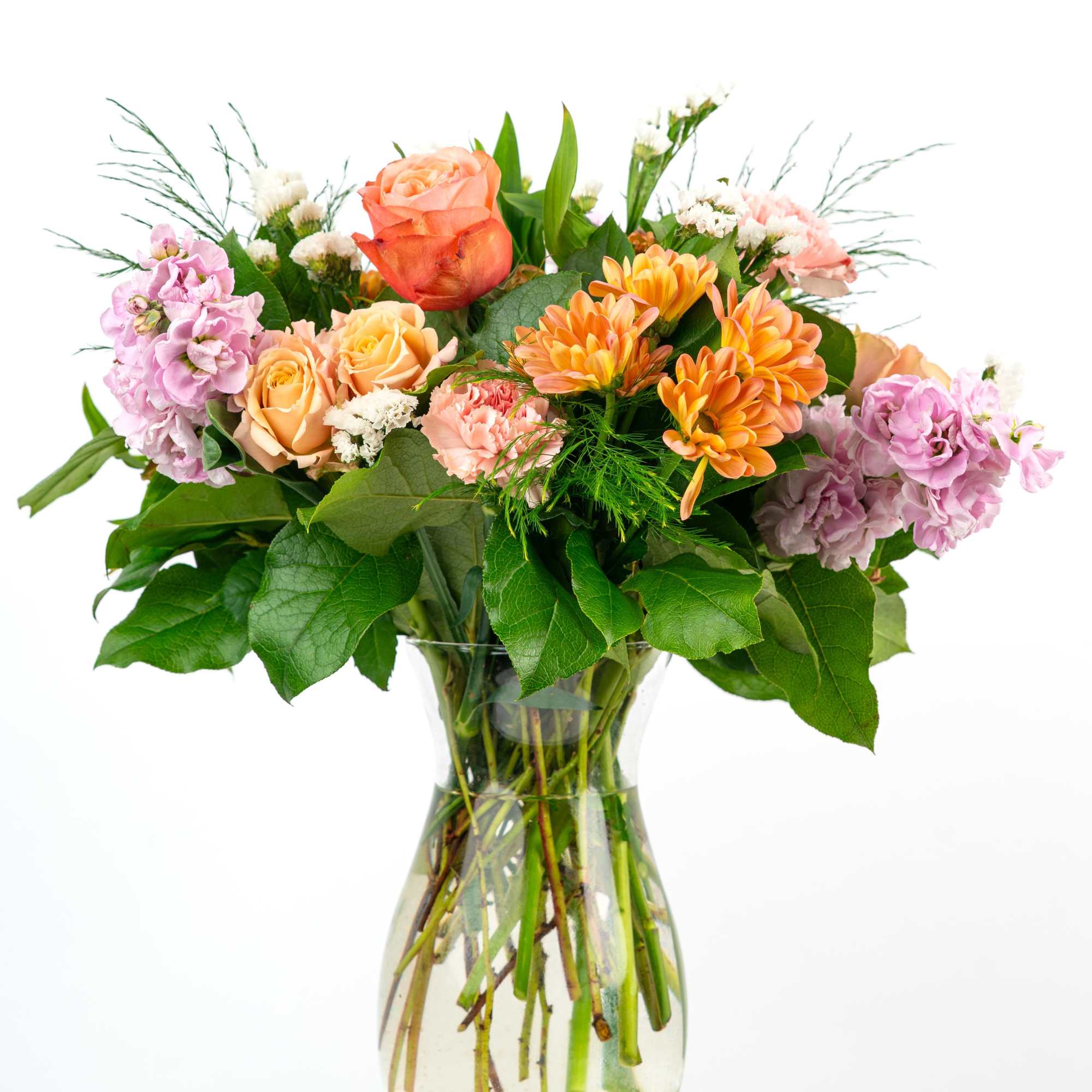 Mixed bouquet of roses, carnations, and orange daisies in a glass vase