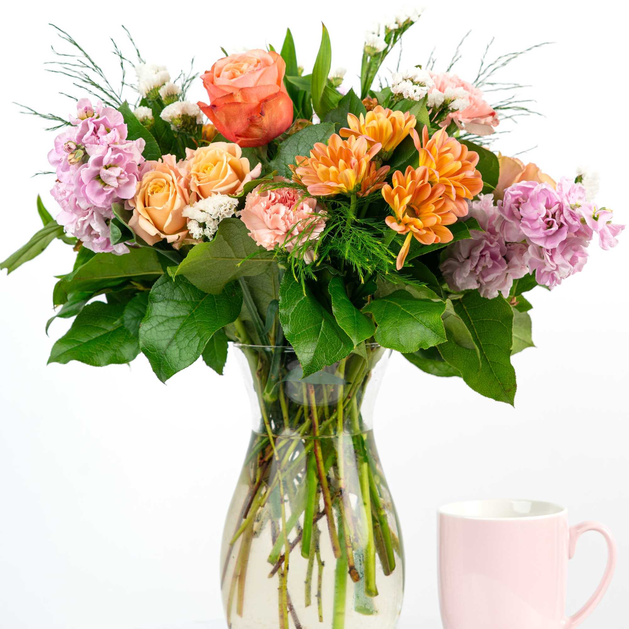Mixed bouquet of roses, chrysanthemums, and pink flowers in a glass vase