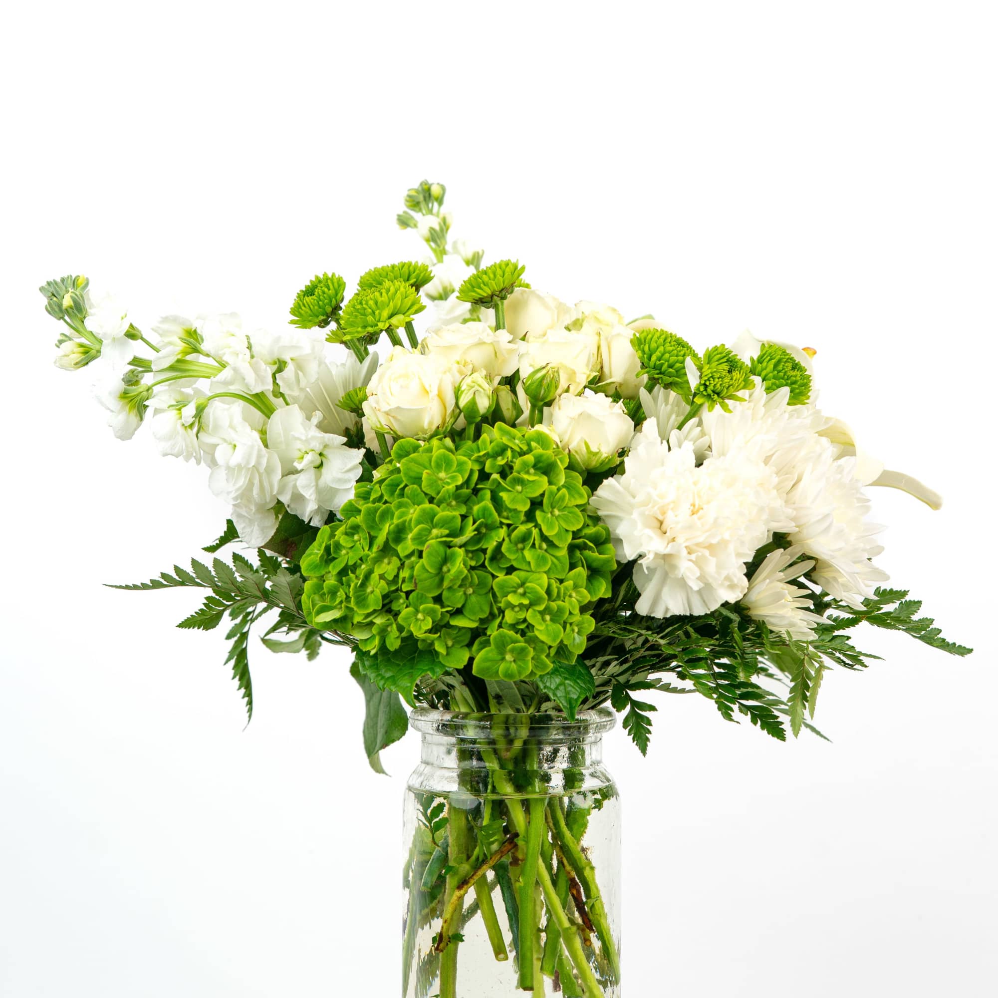 White and green mixed flower arrangement in a clear glass jar vase