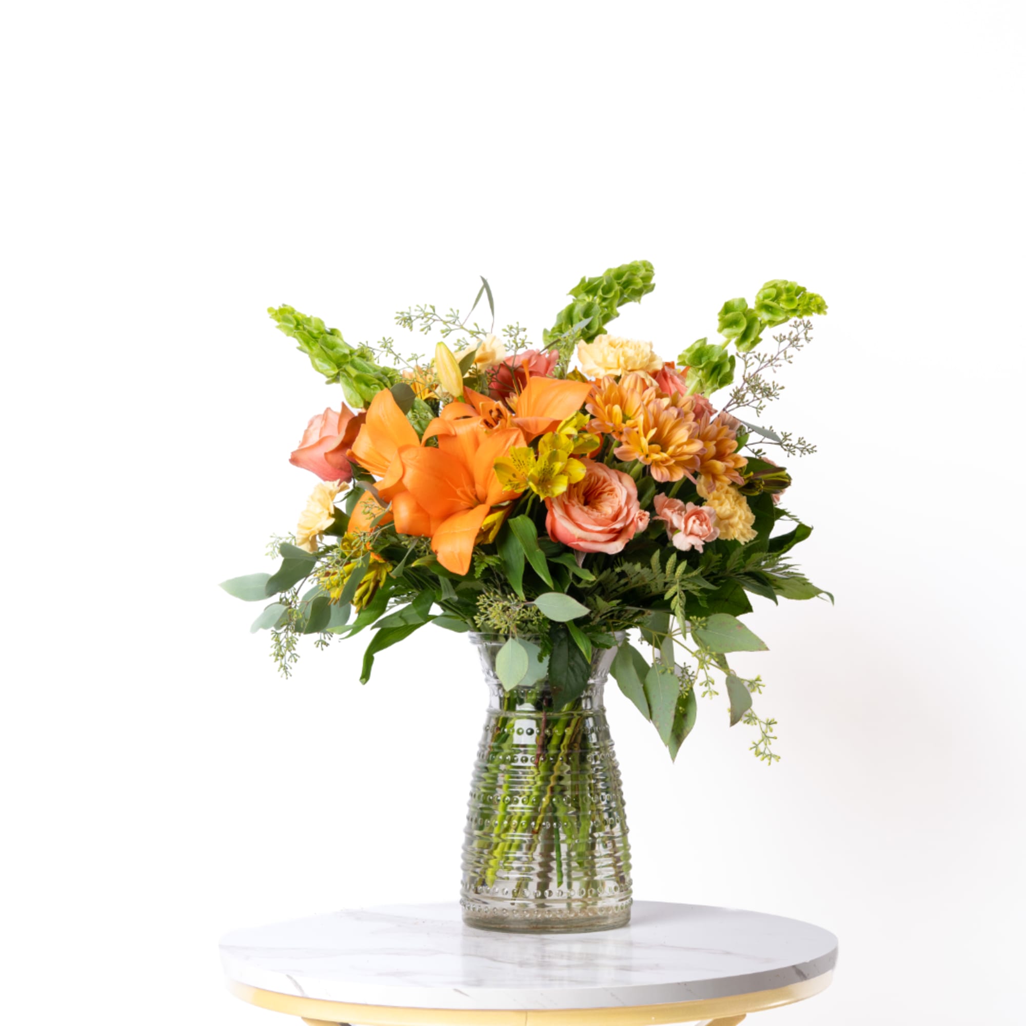 Orange and peach mixed bouquet in a clear glass vase