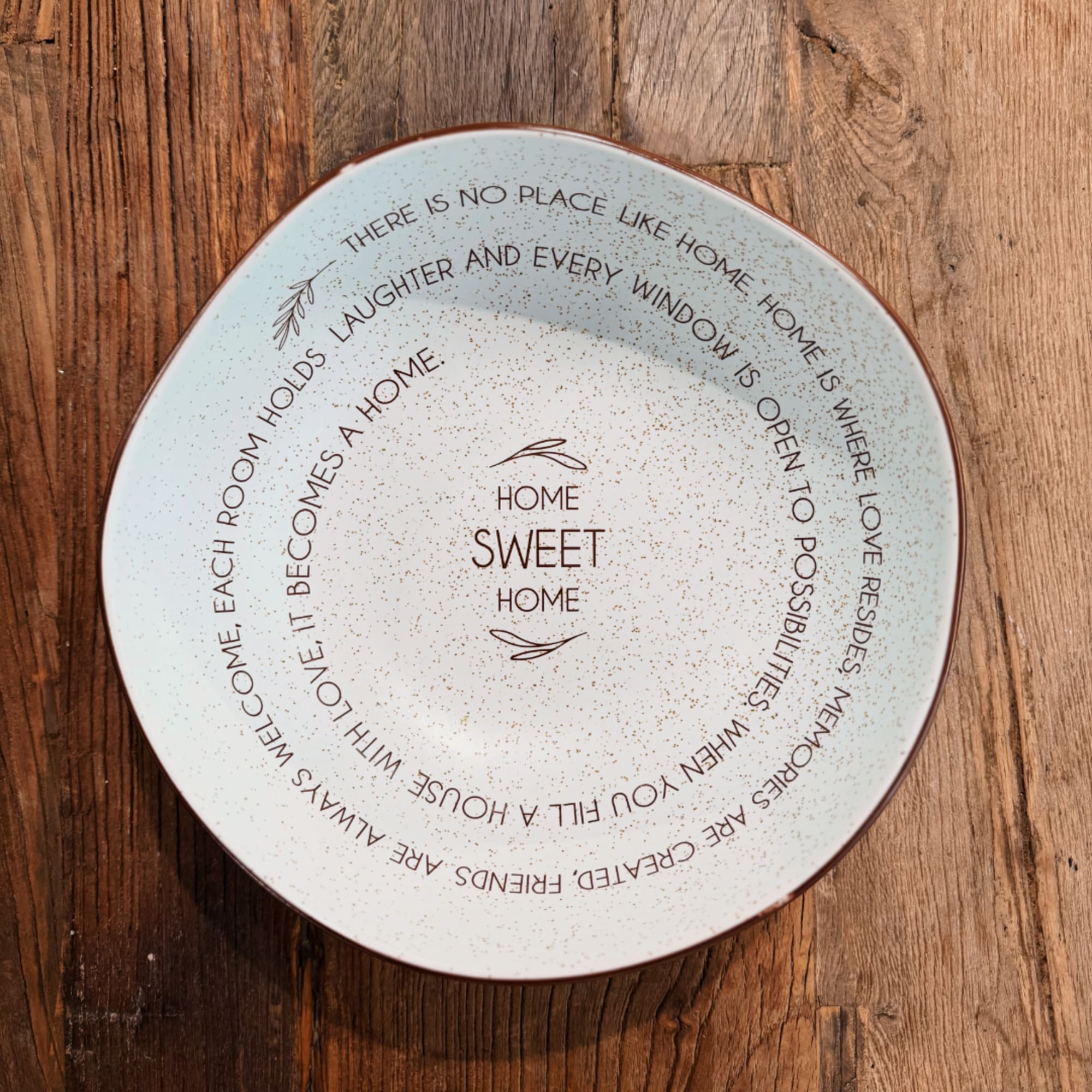 Decorative ceramic plate with "Home Sweet Home" text on a wooden surface