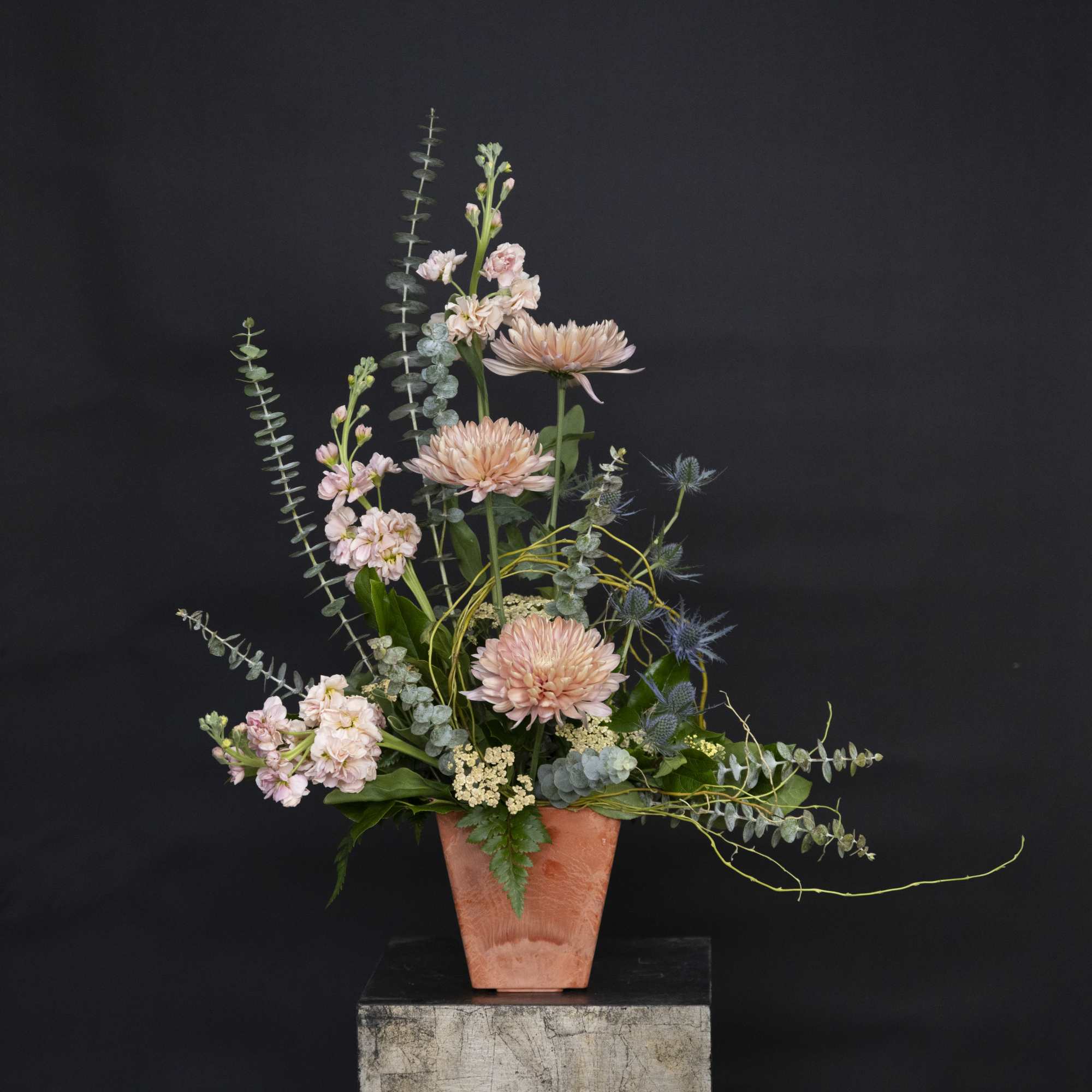 Tall pastel floral arrangement in a terracotta vase