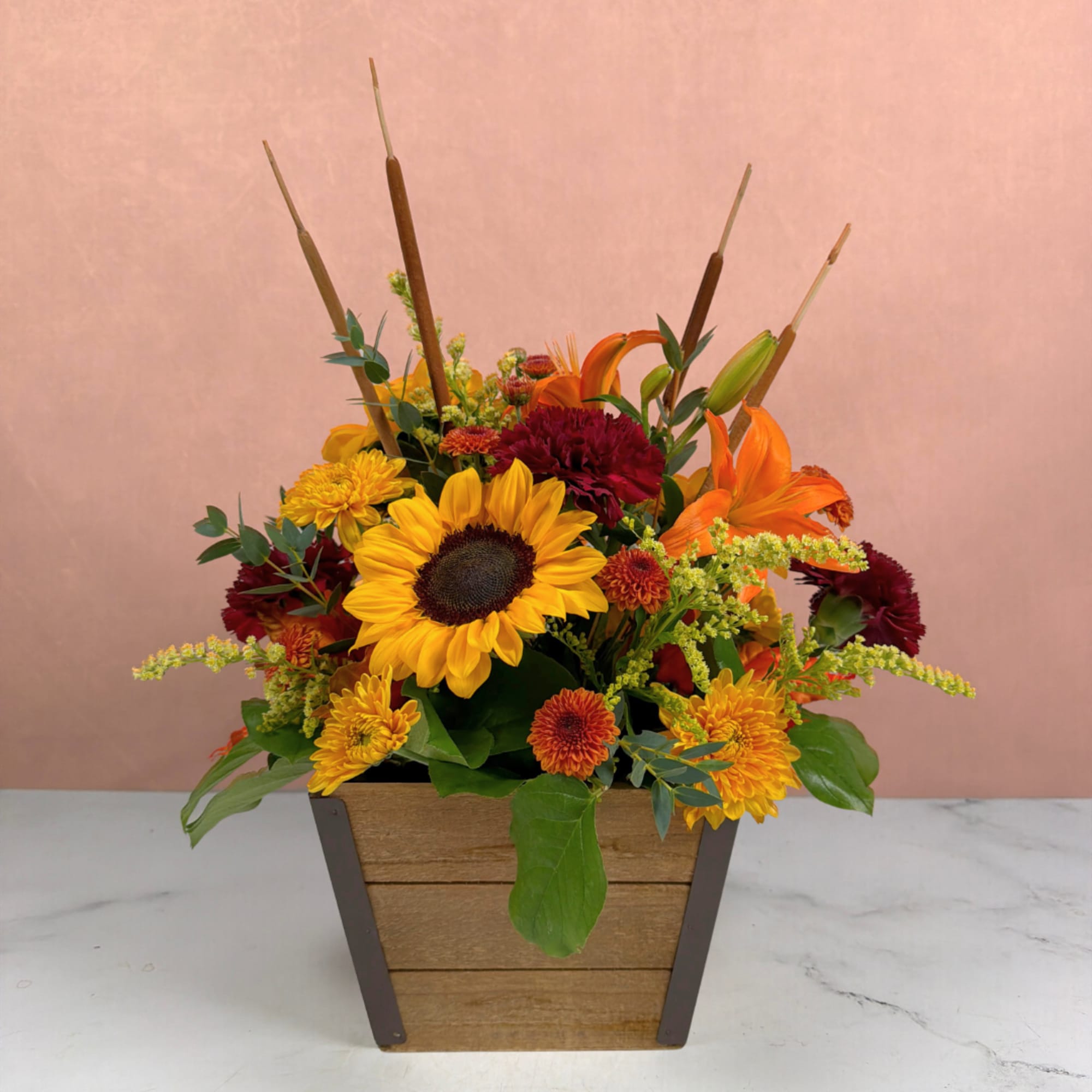 Mixed autumn bouquet in a wooden box with sunflowers, lilies, and chrysanthemums