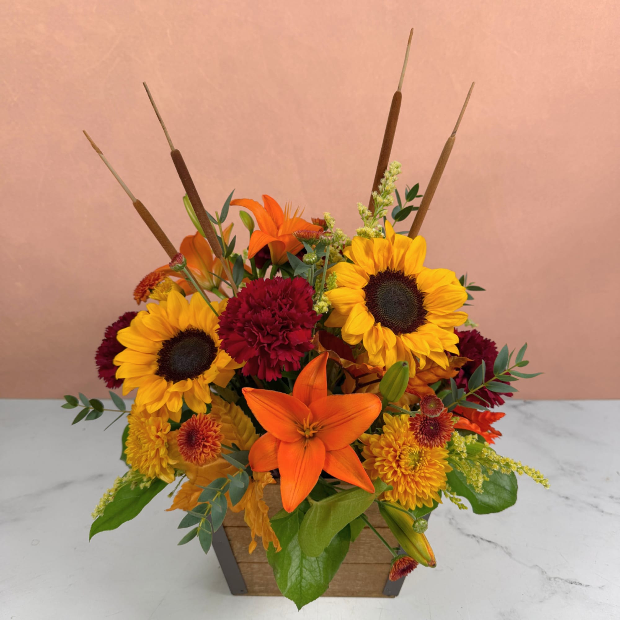 Bright sunflower and lily arrangement in a wooden container