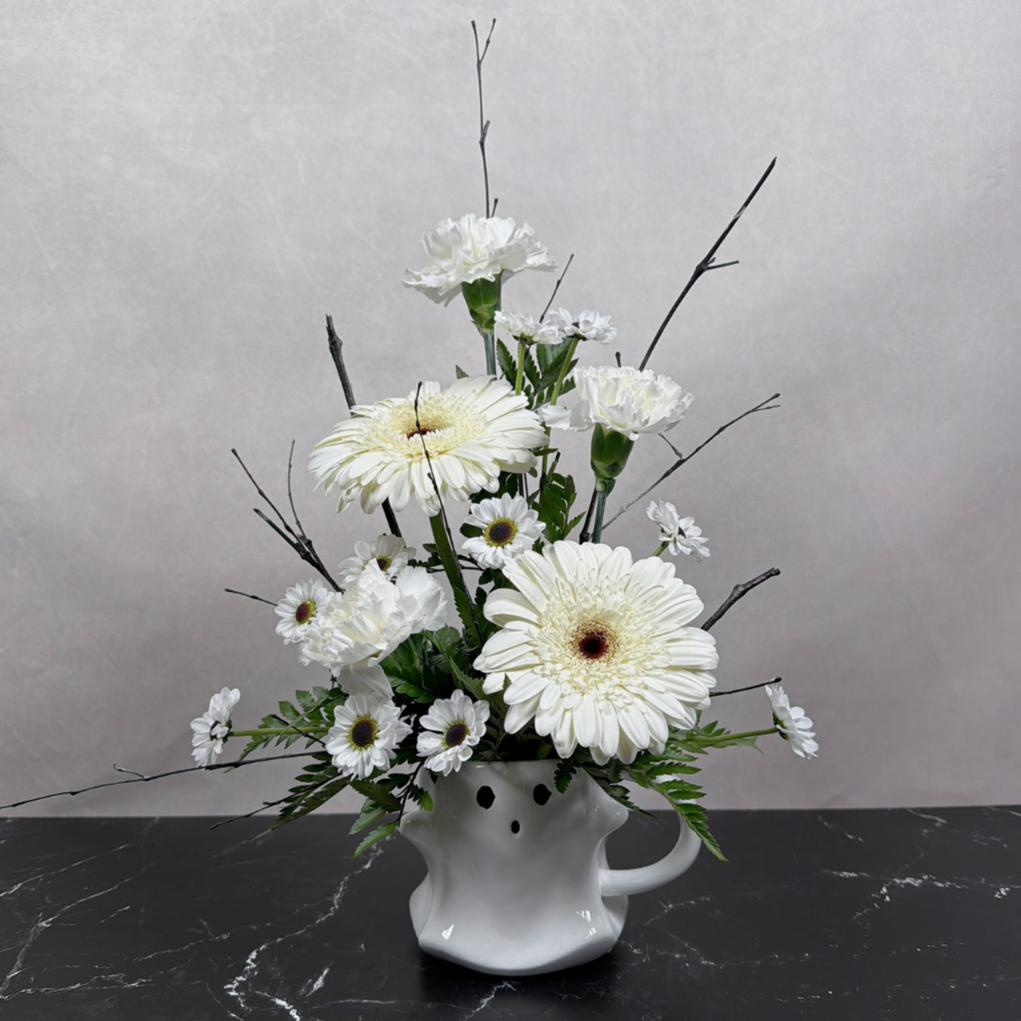 White gerbera daisies and carnations arranged in a white ceramic vase