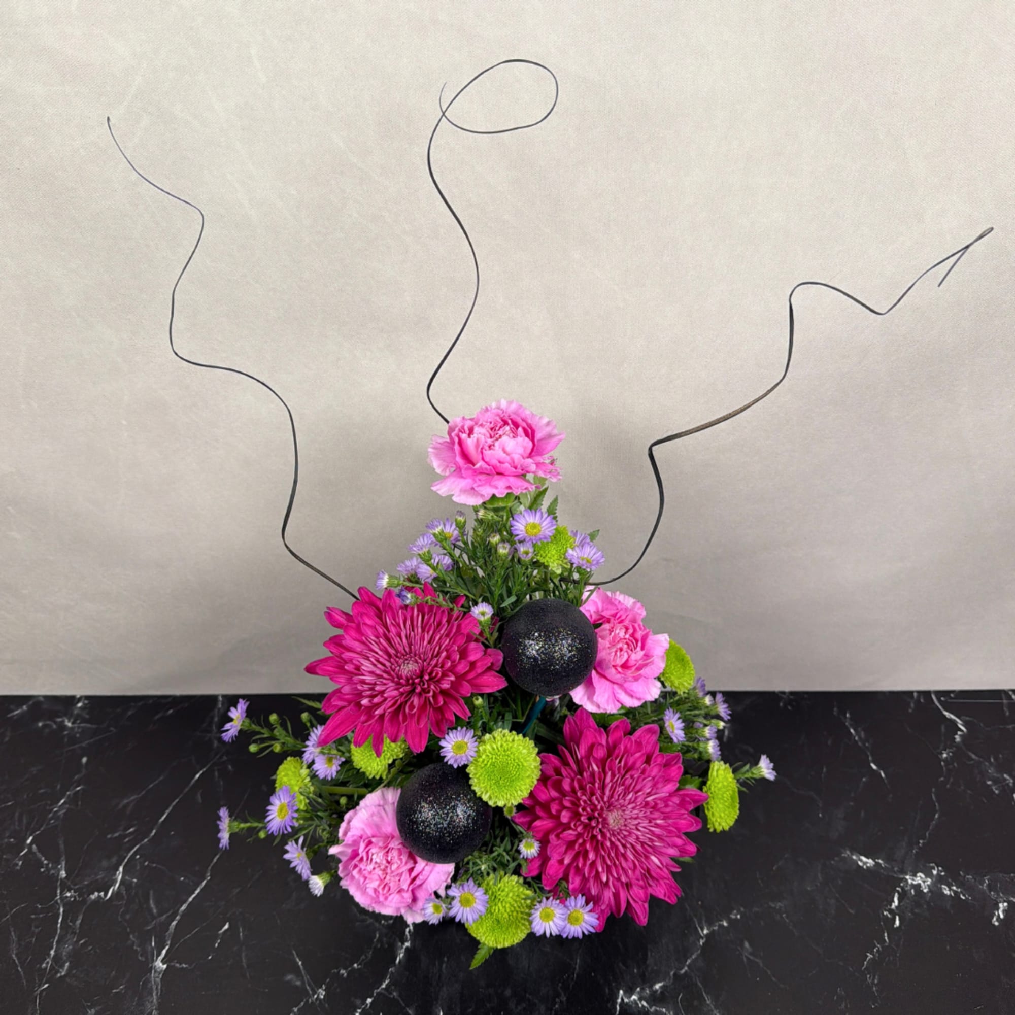 Pink and purple floral arrangement with black decorative spheres