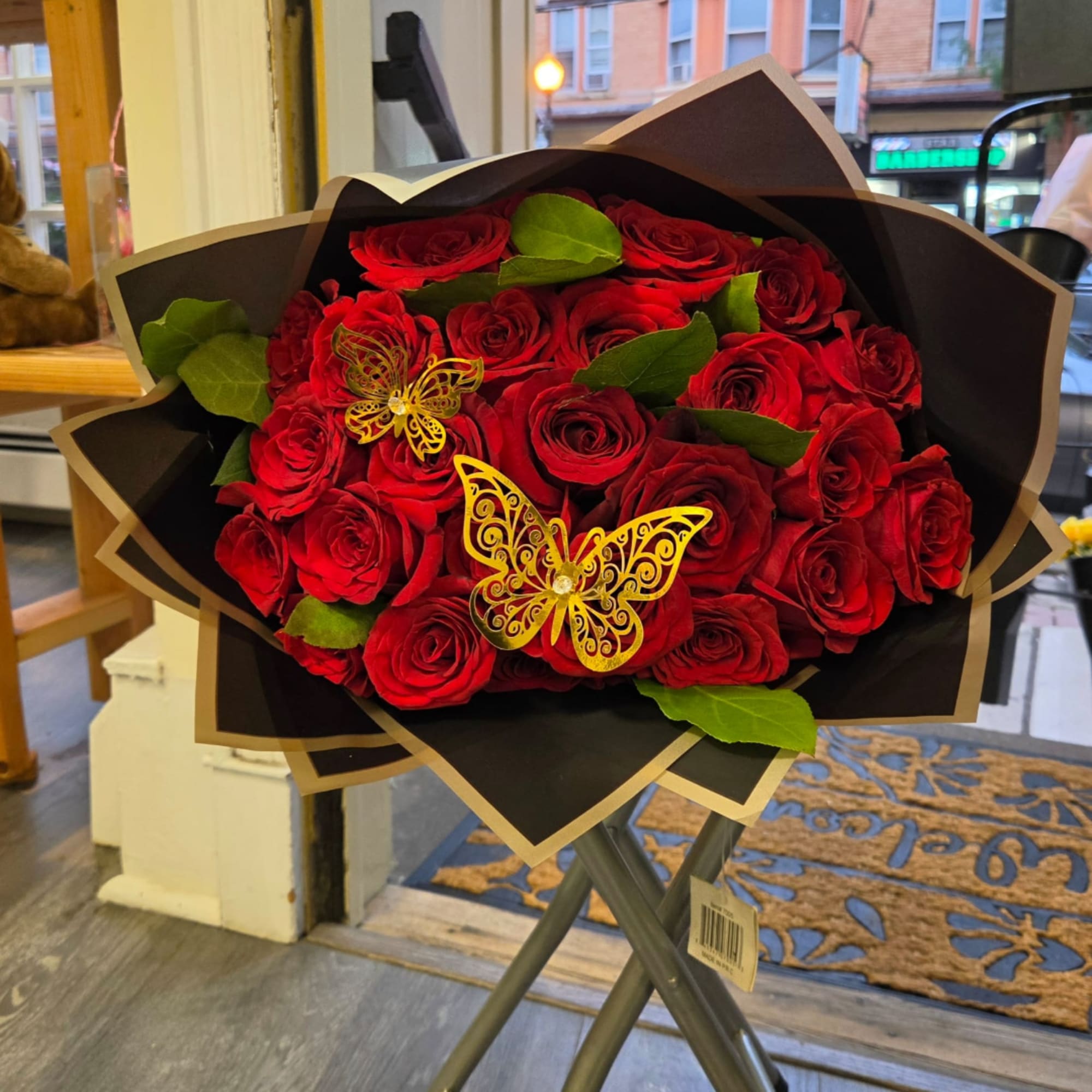 Bouquet of red roses wrapped in dark paper with butterfly decorations