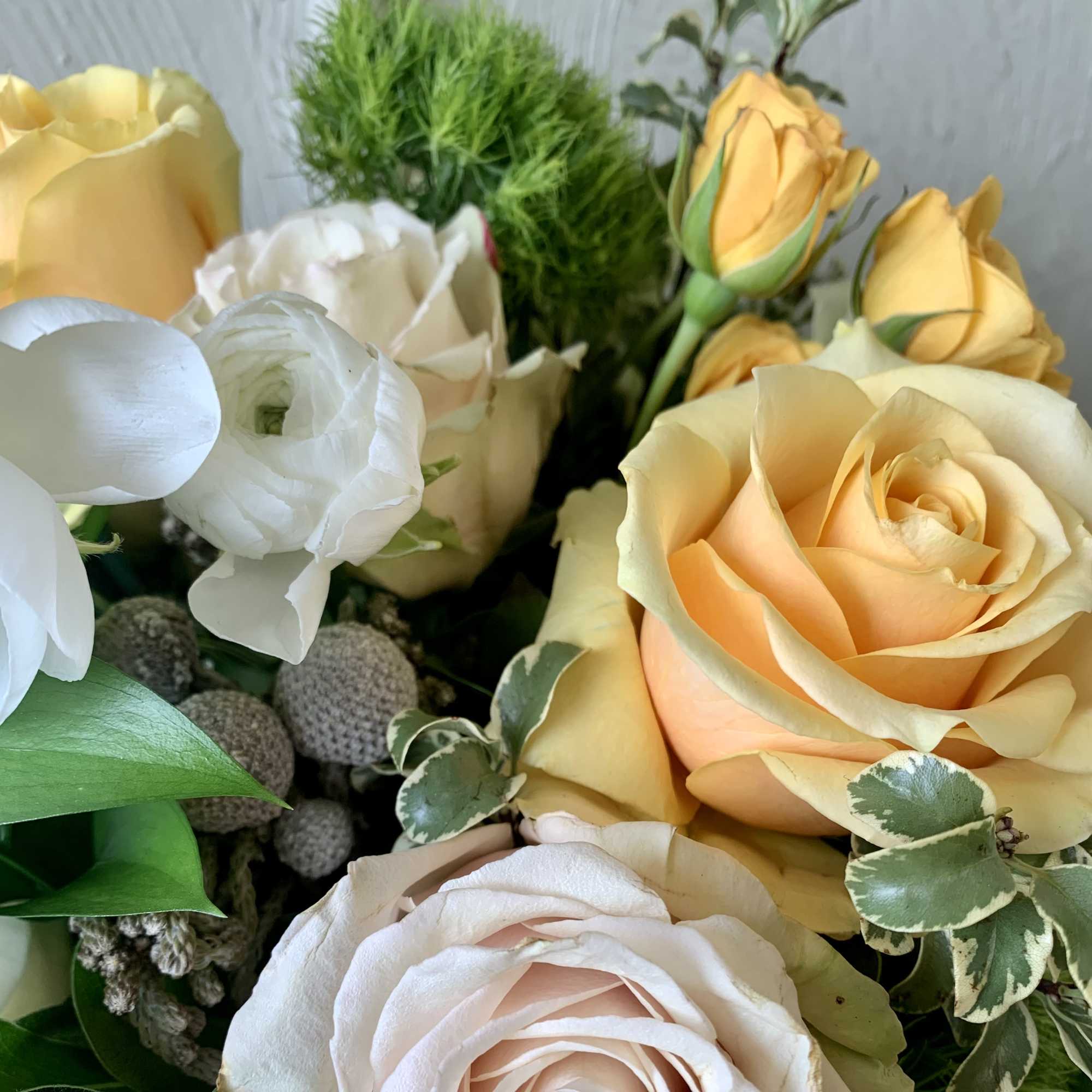 Bouquet of peach, white, and yellow roses with green accents