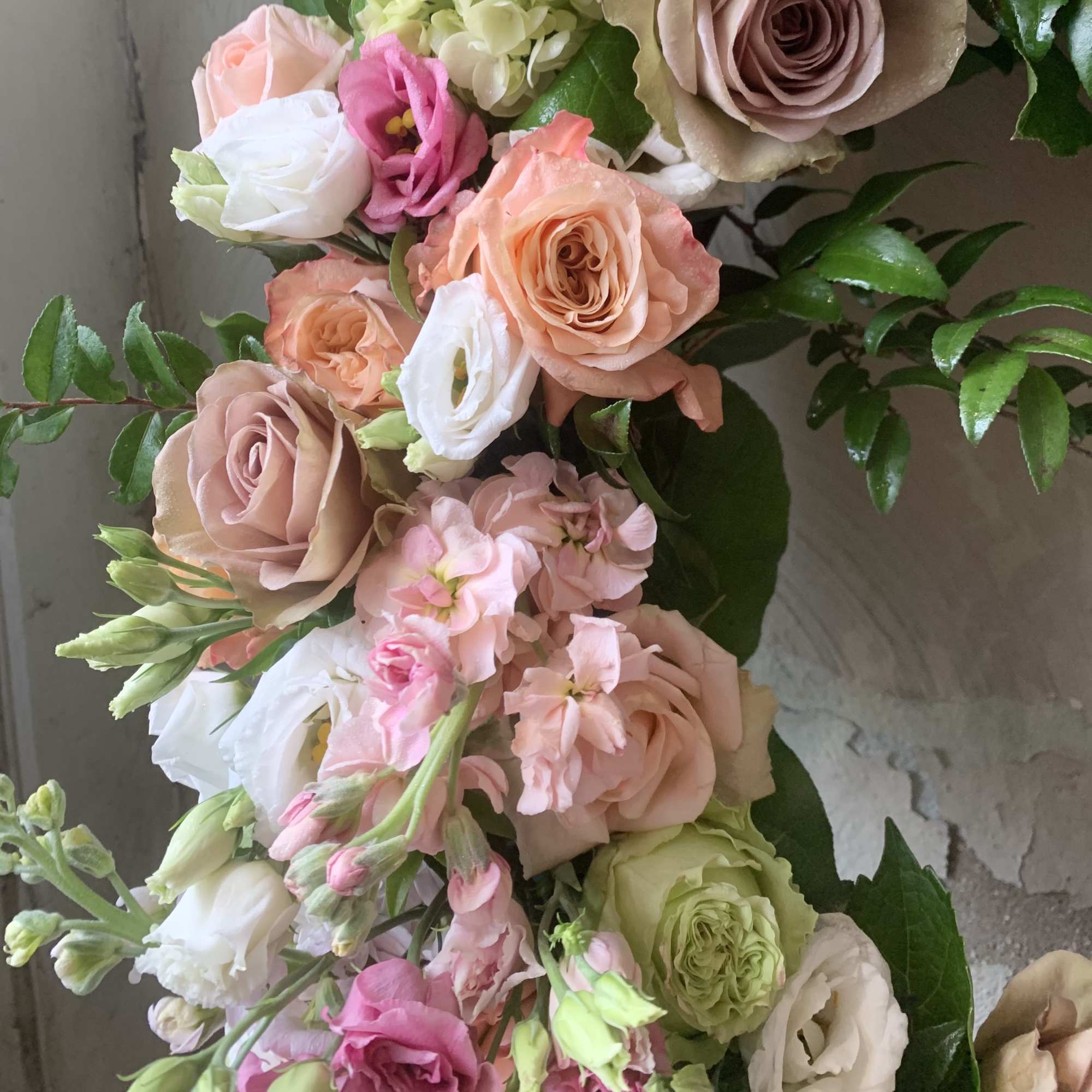Bouquet of pastel roses and lisianthus with green foliage