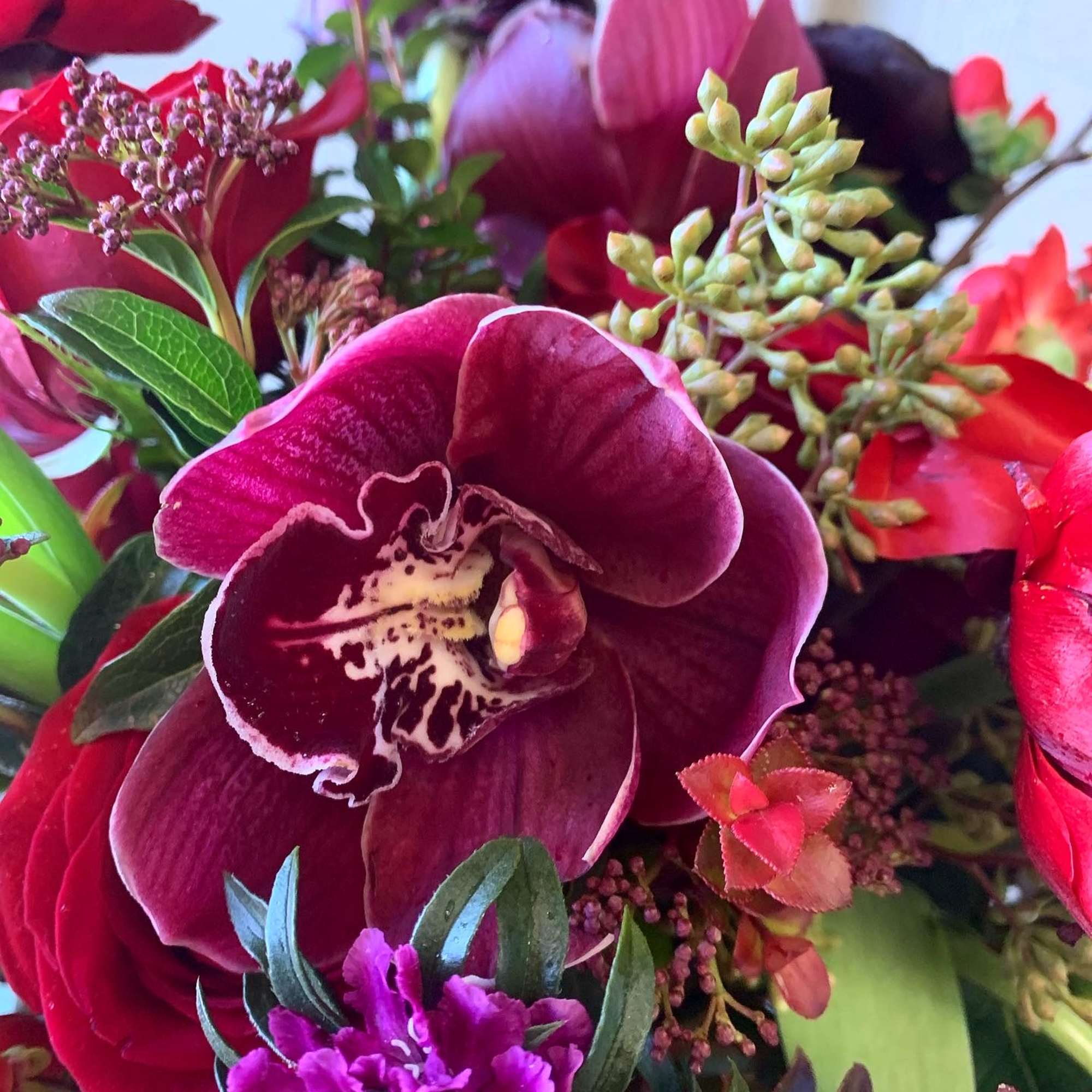 Close-up bouquet with a burgundy orchid and red blooms