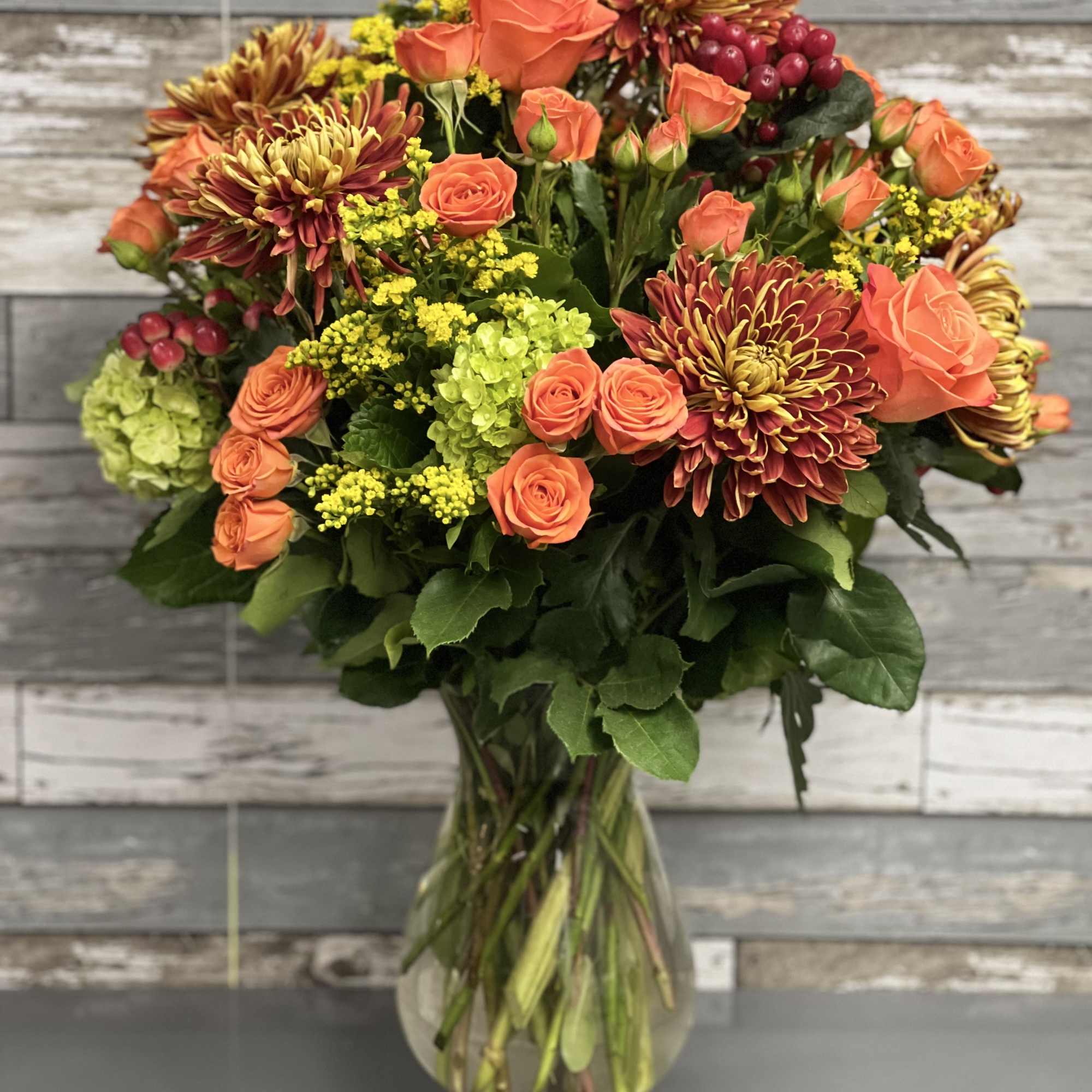 Orange roses and chrysanthemums in a clear glass vase