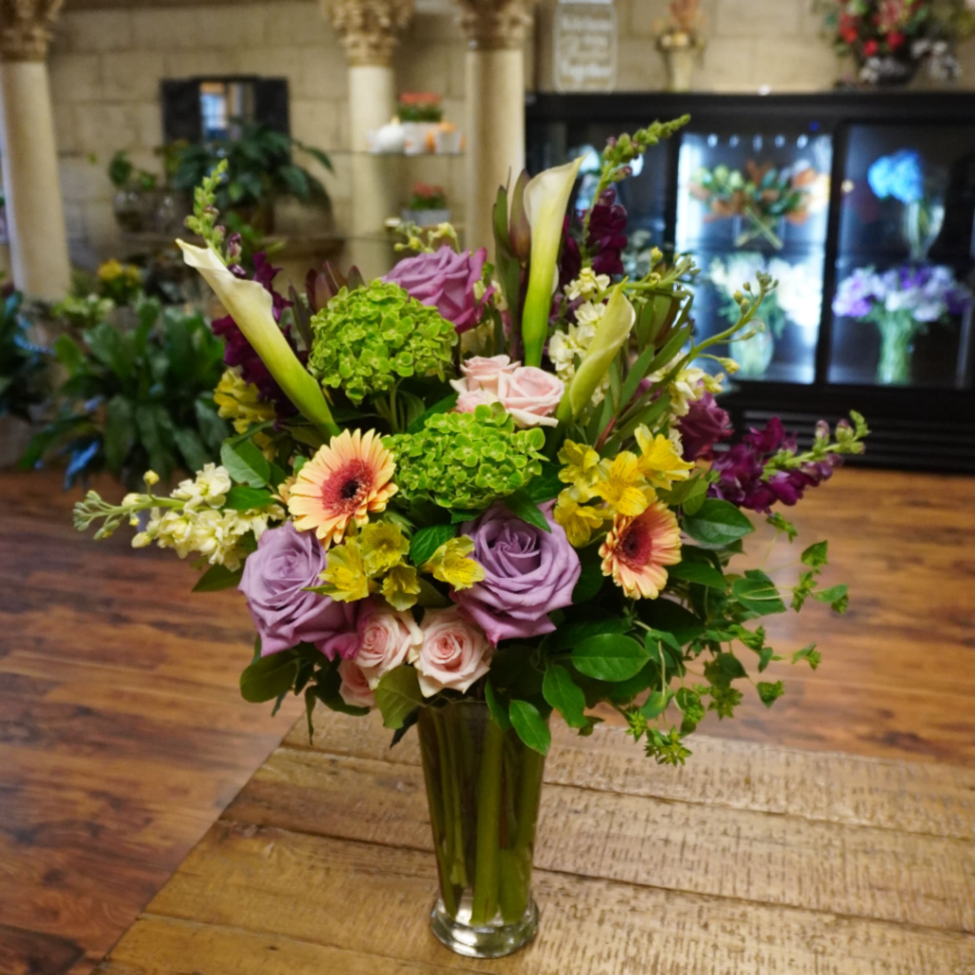 Mixed bouquet in a clear glass vase with roses, calla lilies, and gerbera daisies