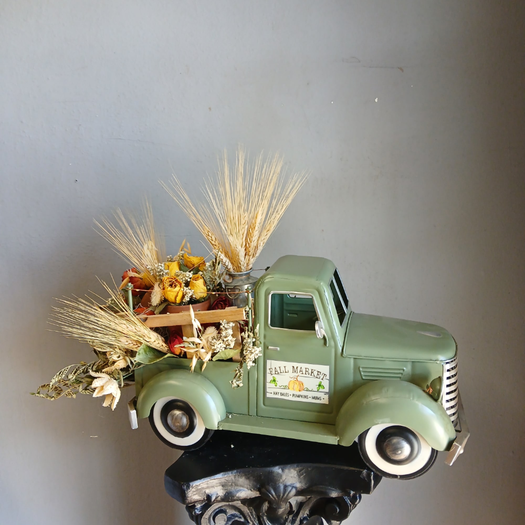 Green vintage truck filled with dried flowers and wheat