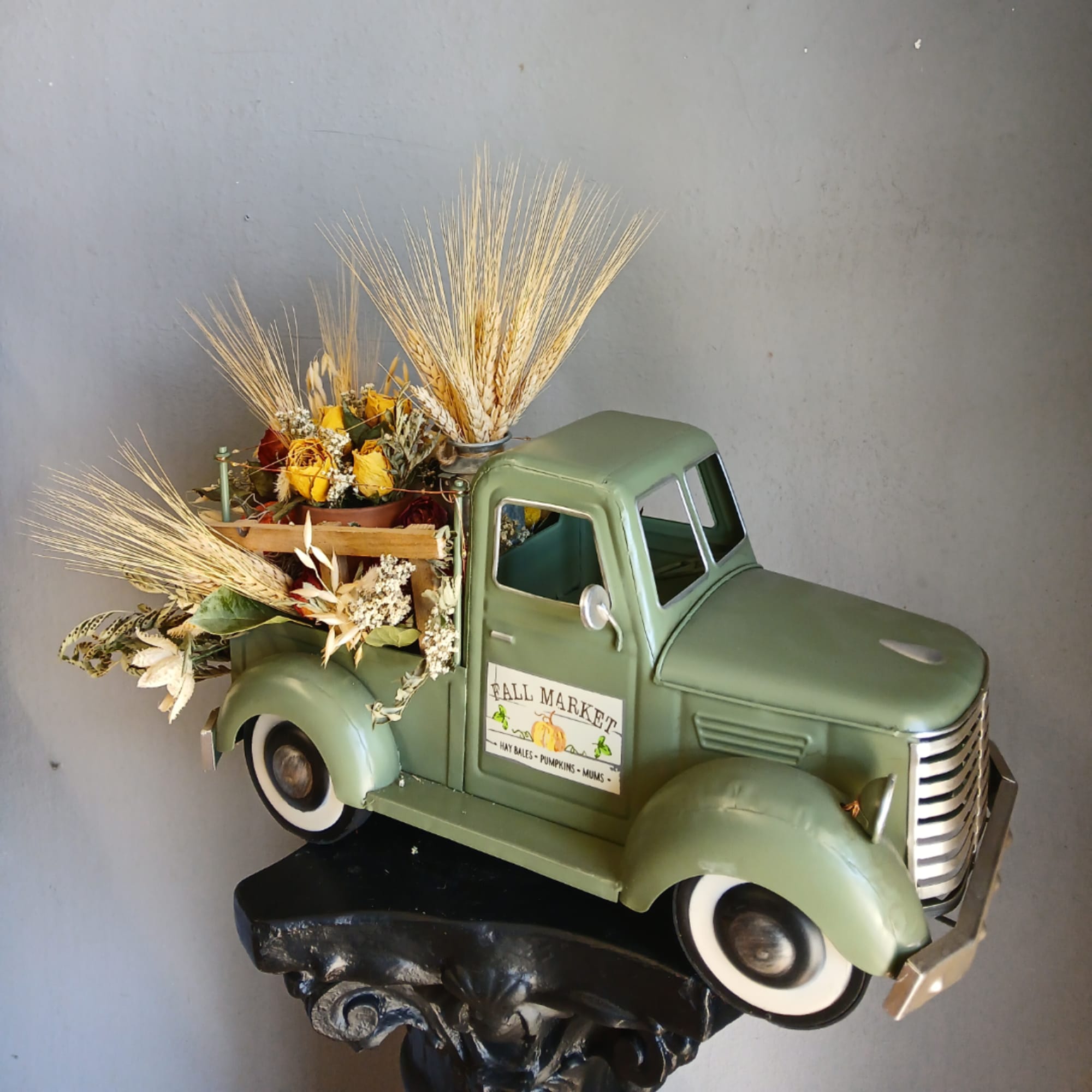 Decorative green truck filled with dried flowers and wheat stalks