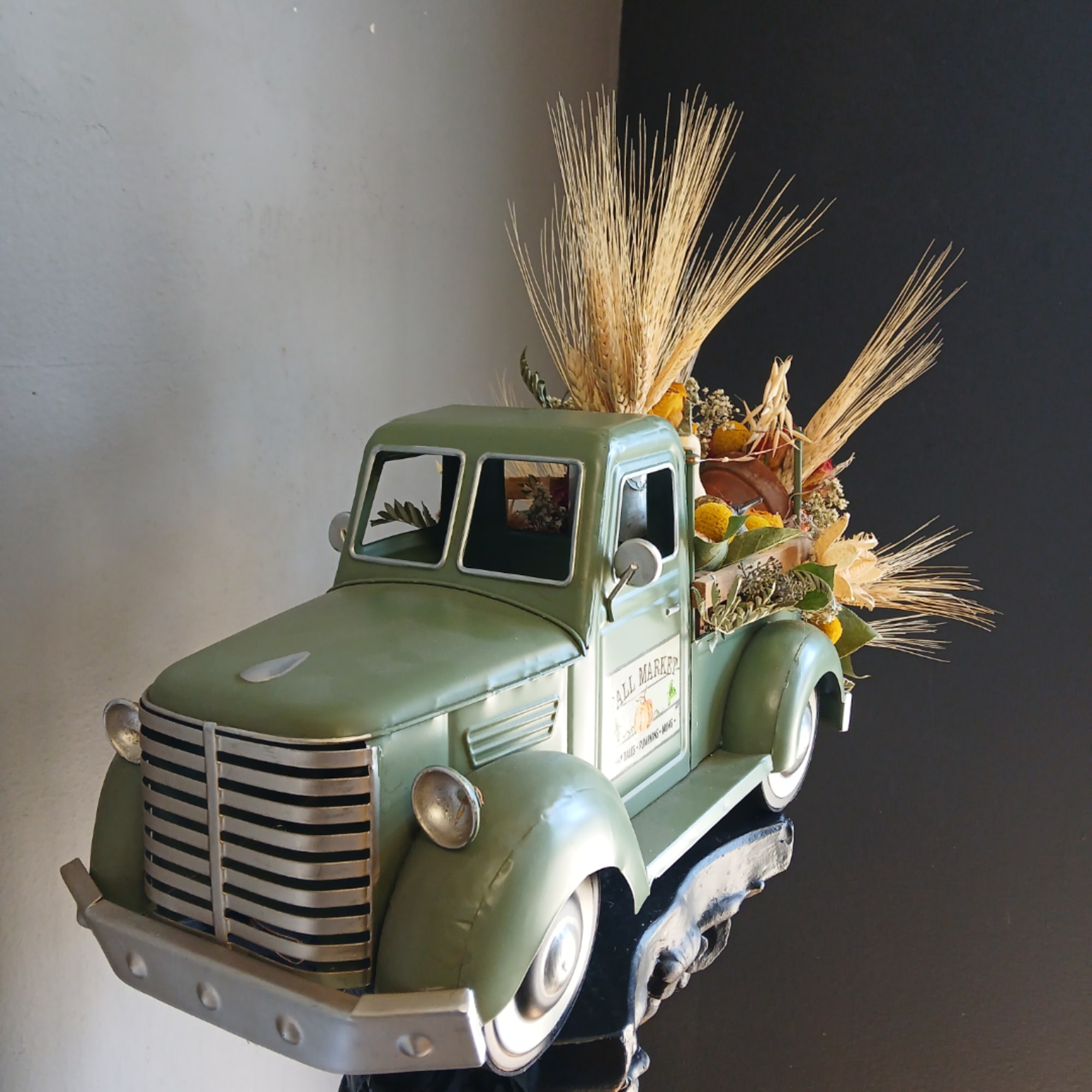 Vintage green truck decorated with dried flowers and wheat