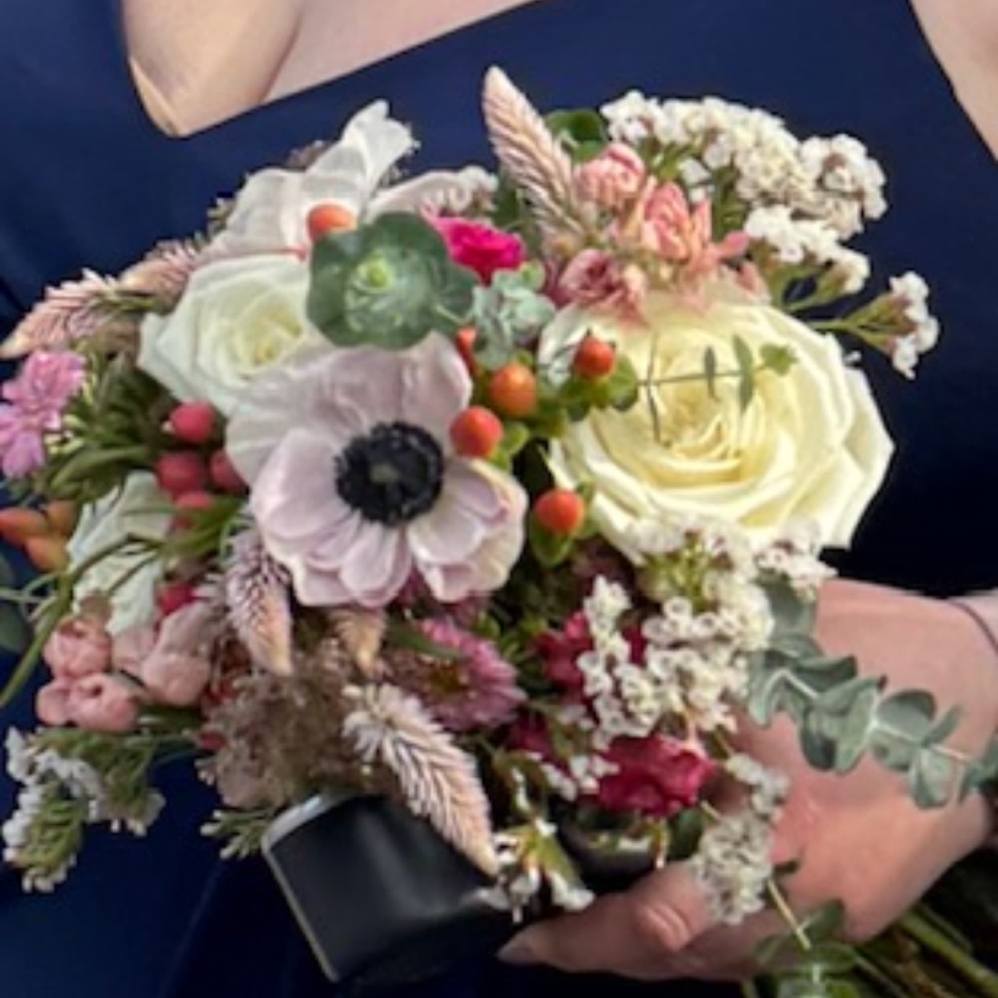 Handheld bouquet with white and pink flowers and mixed greenery