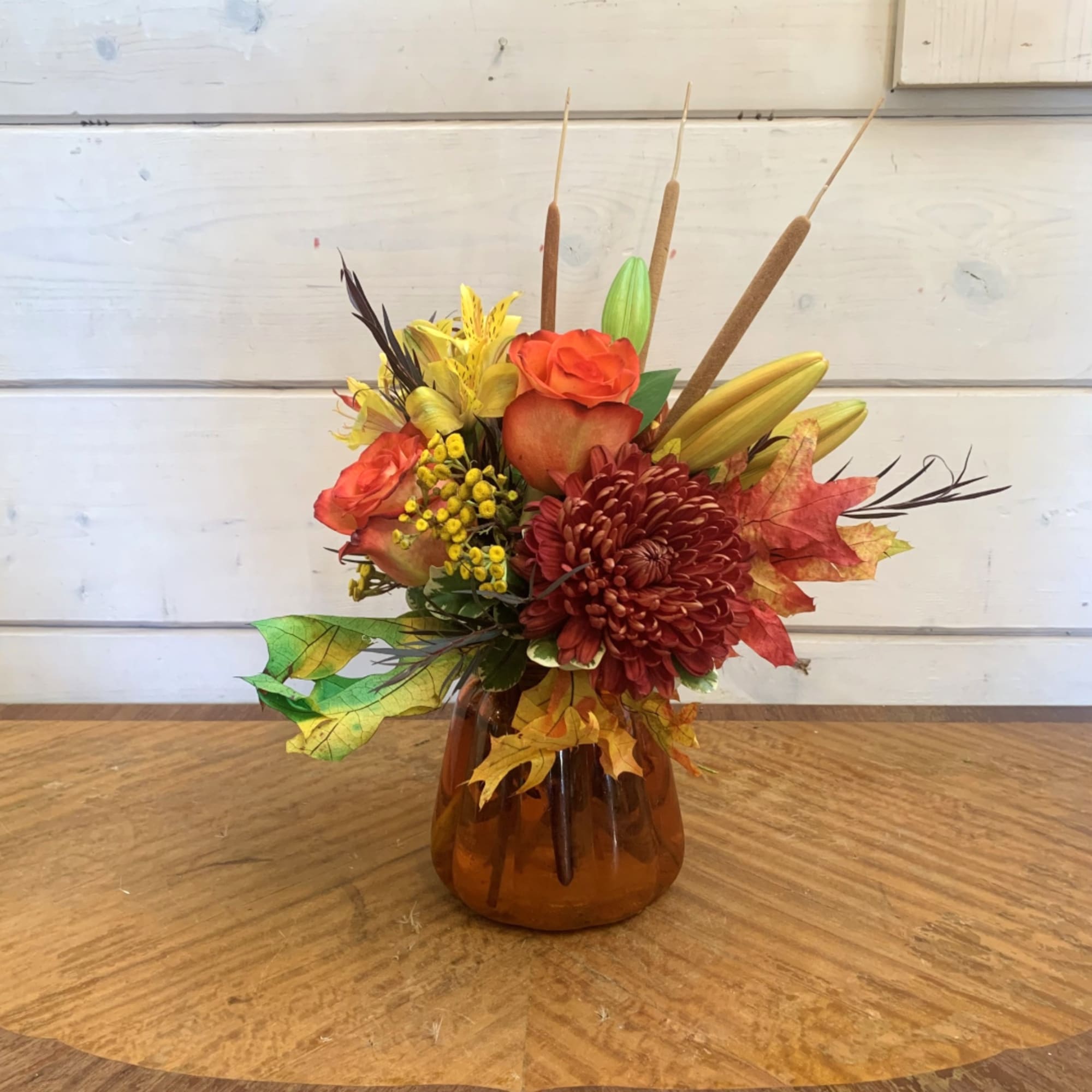 Autumn floral arrangement in an amber glass vase with orange and yellow blooms, photo 2 of 2
