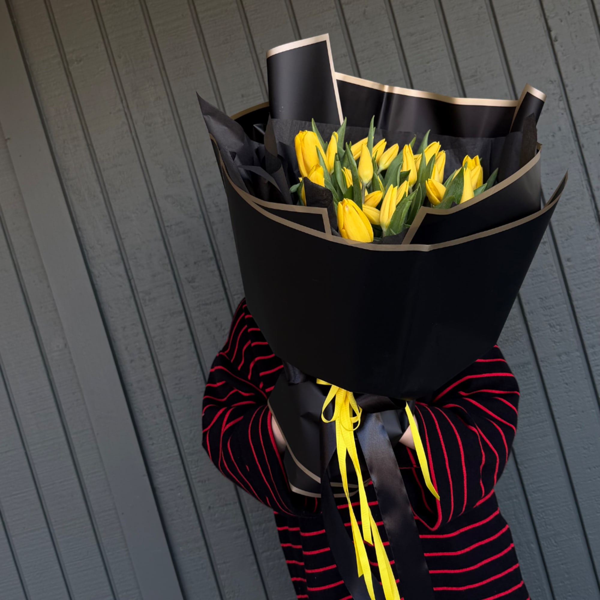 Yellow tulip bouquet wrapped in black paper with ribbon