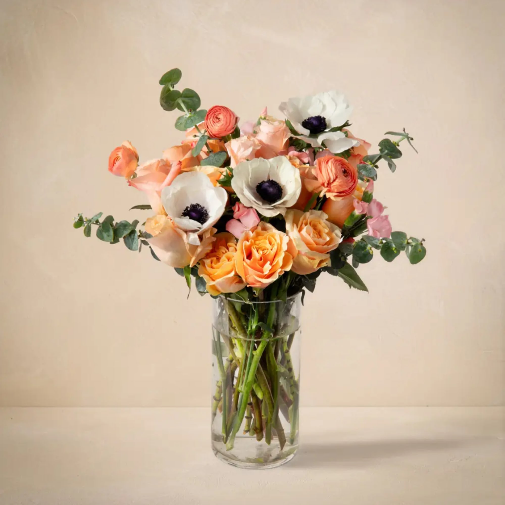 Peach and white flowers in a clear glass vase