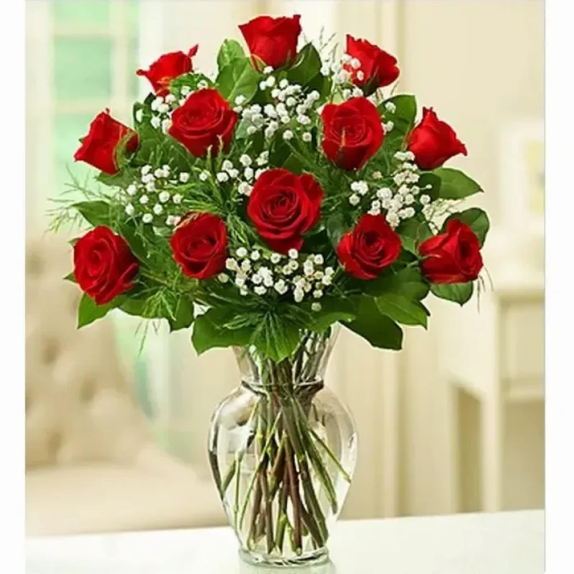 Red roses arranged in a clear glass vase with baby's breath