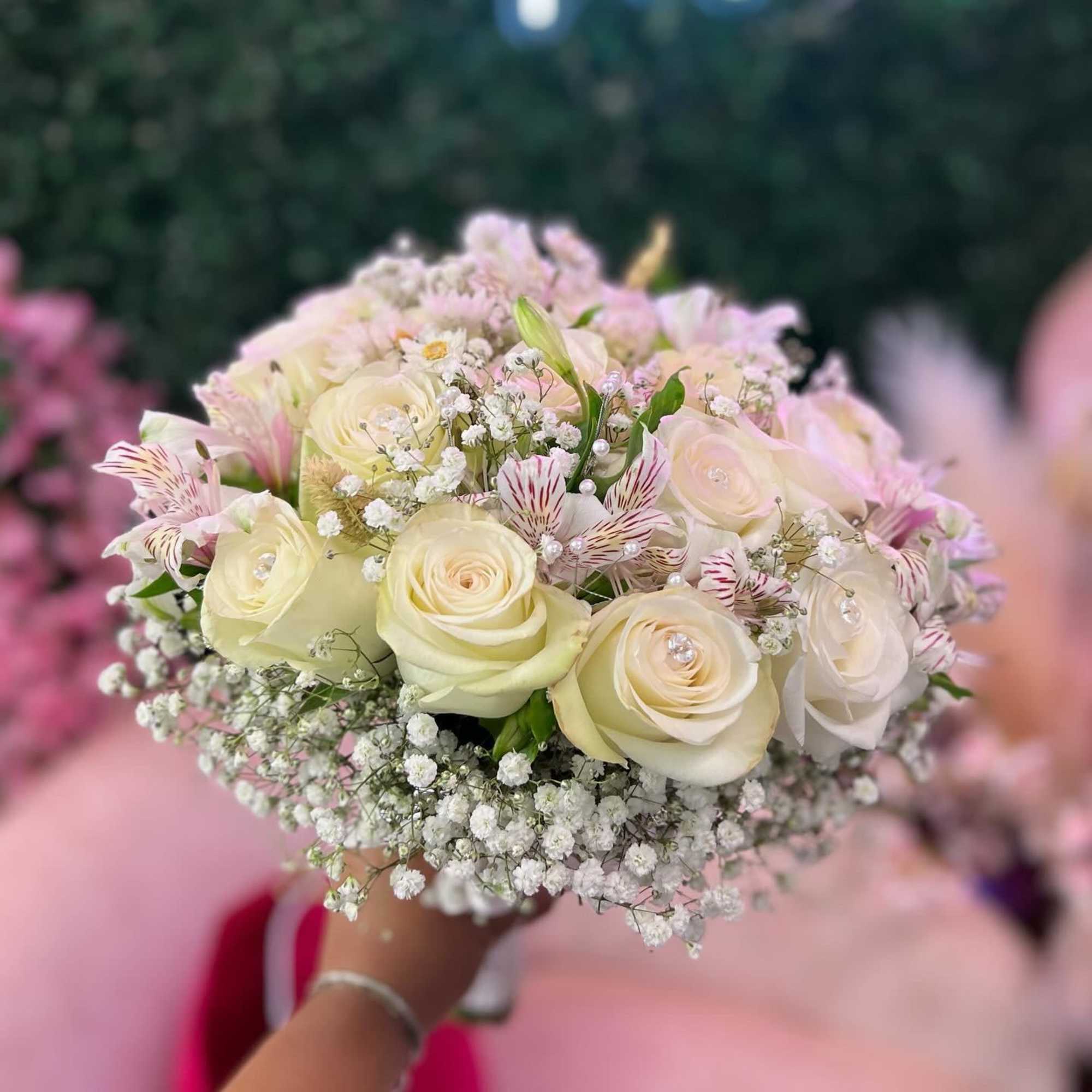 Handheld bouquet of cream roses and small white filler flowers