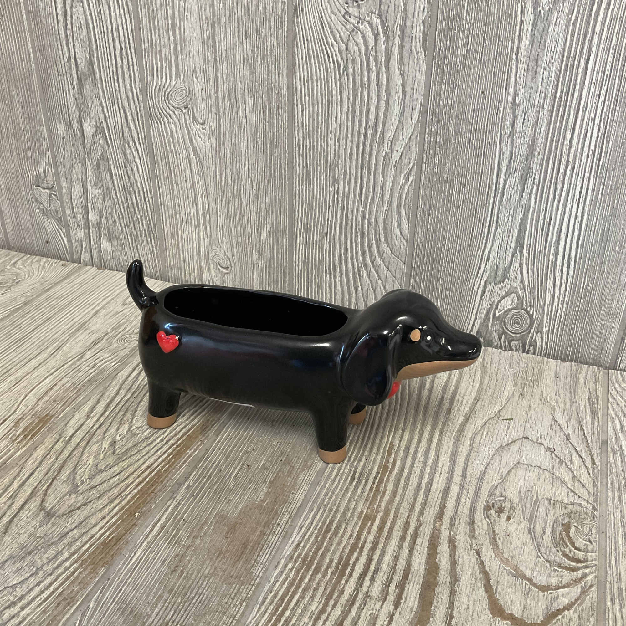 Black dachshund-shaped ceramic planter with a red heart detail