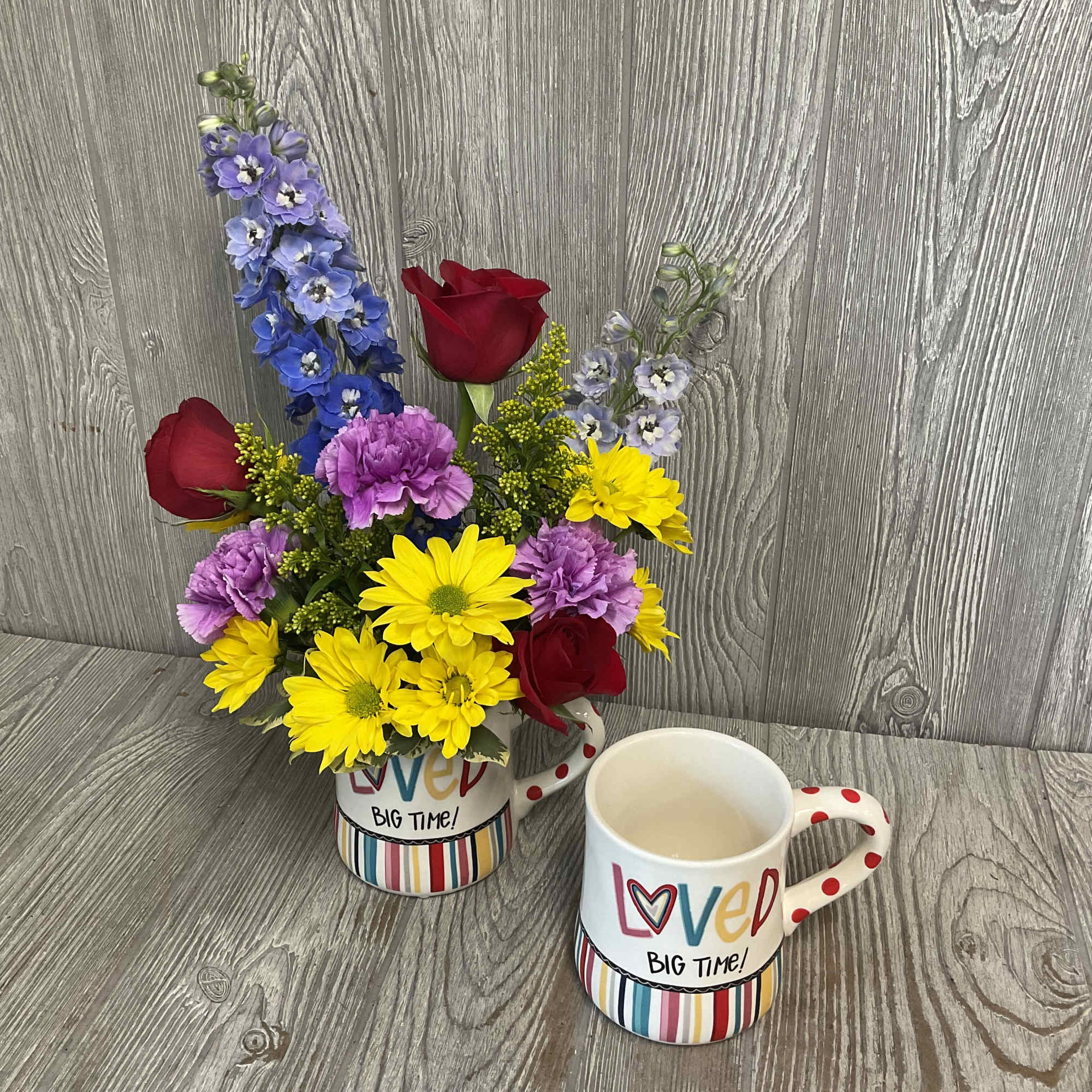 Bouquet of mixed flowers in a decorative mug beside a matching mug