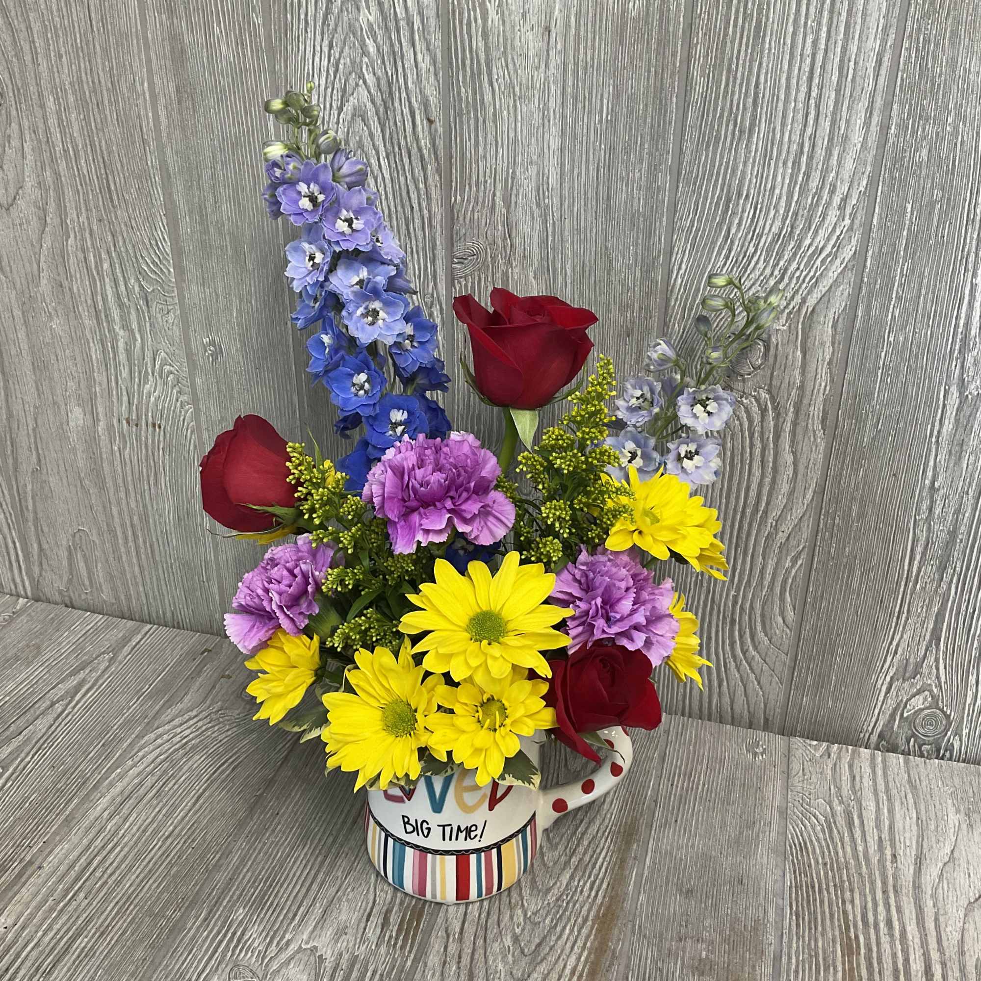 Colorful flower arrangement in a mug with roses, daisies, and purple blooms