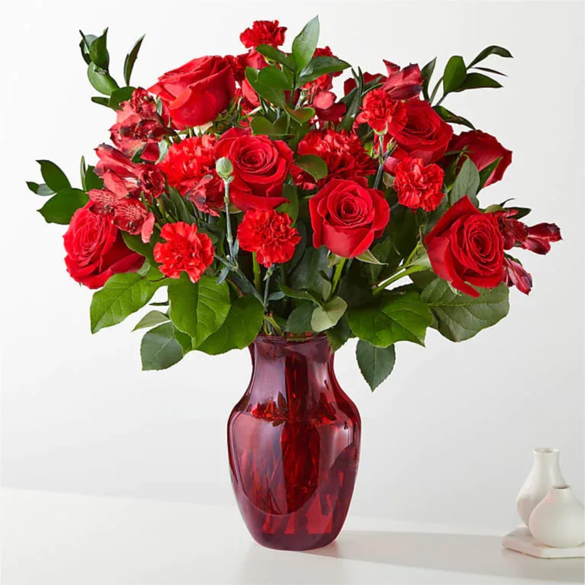 Red roses and carnations in a red glass vase