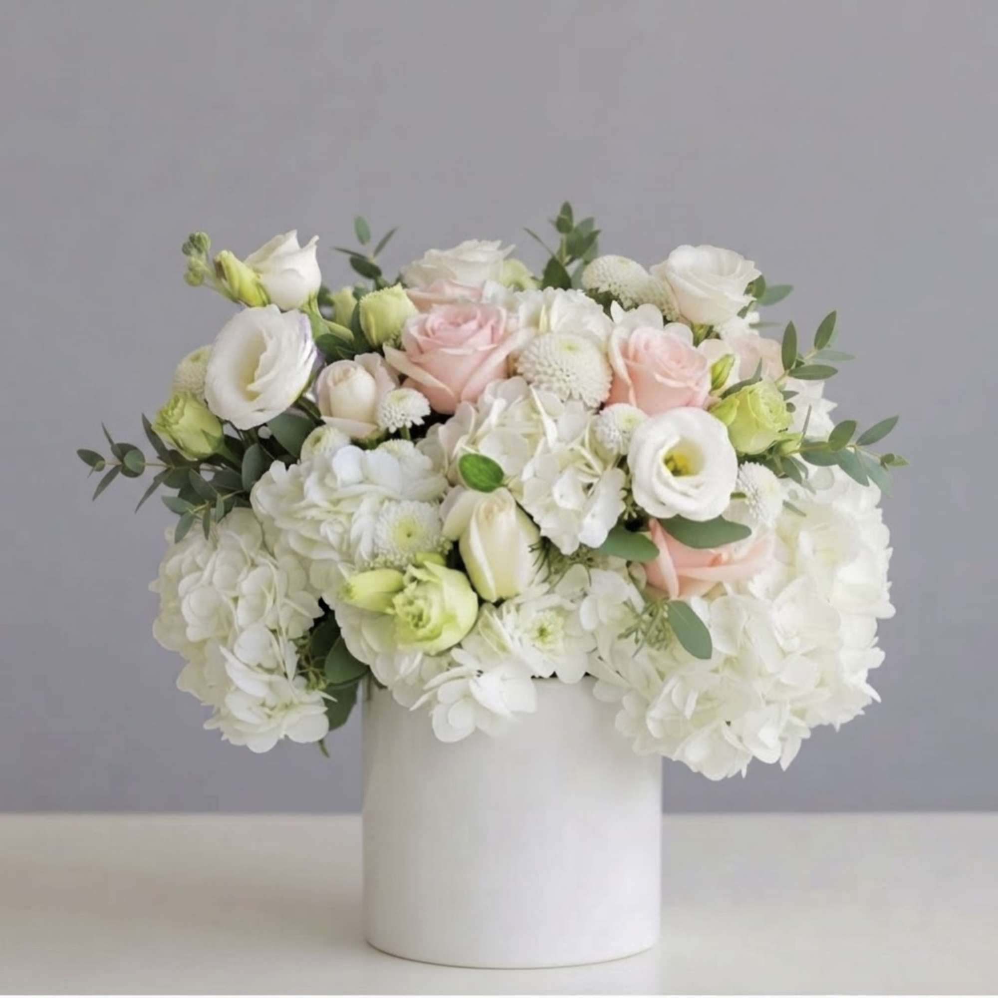 White and blush bouquet in a white cylindrical vase