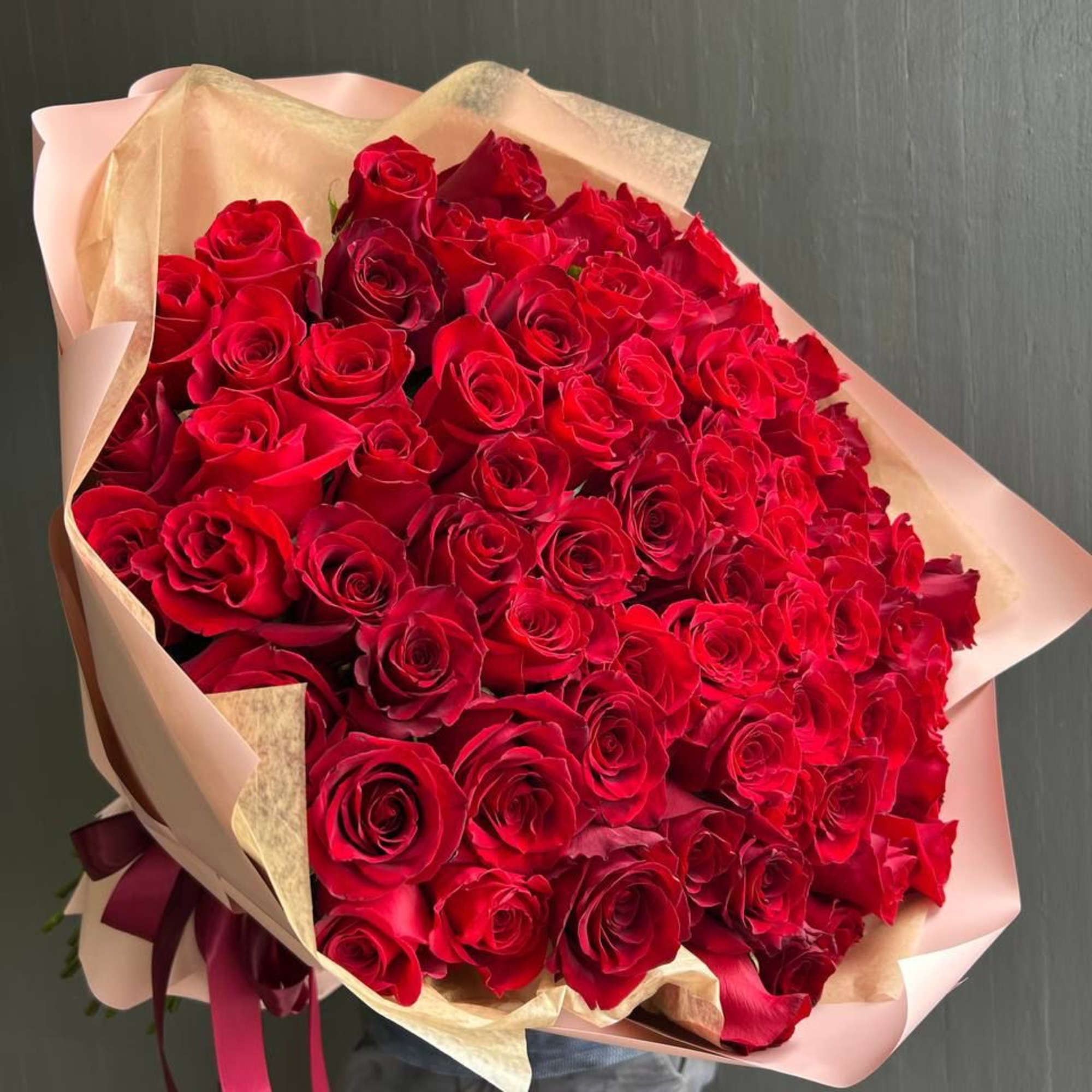 Large bouquet of red roses wrapped in pink and beige paper