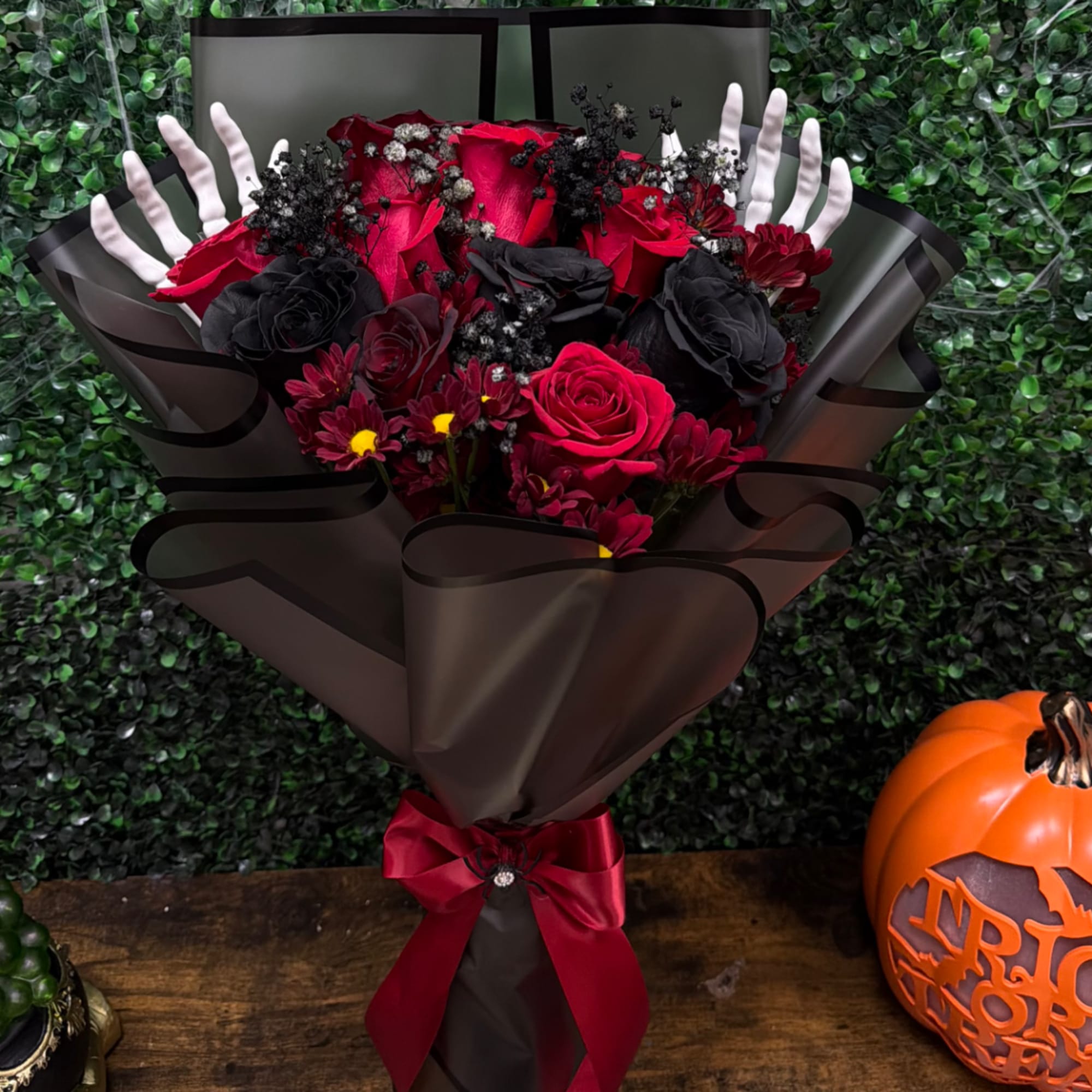 Bouquet of red and black roses wrapped in dark paper with a red ribbon