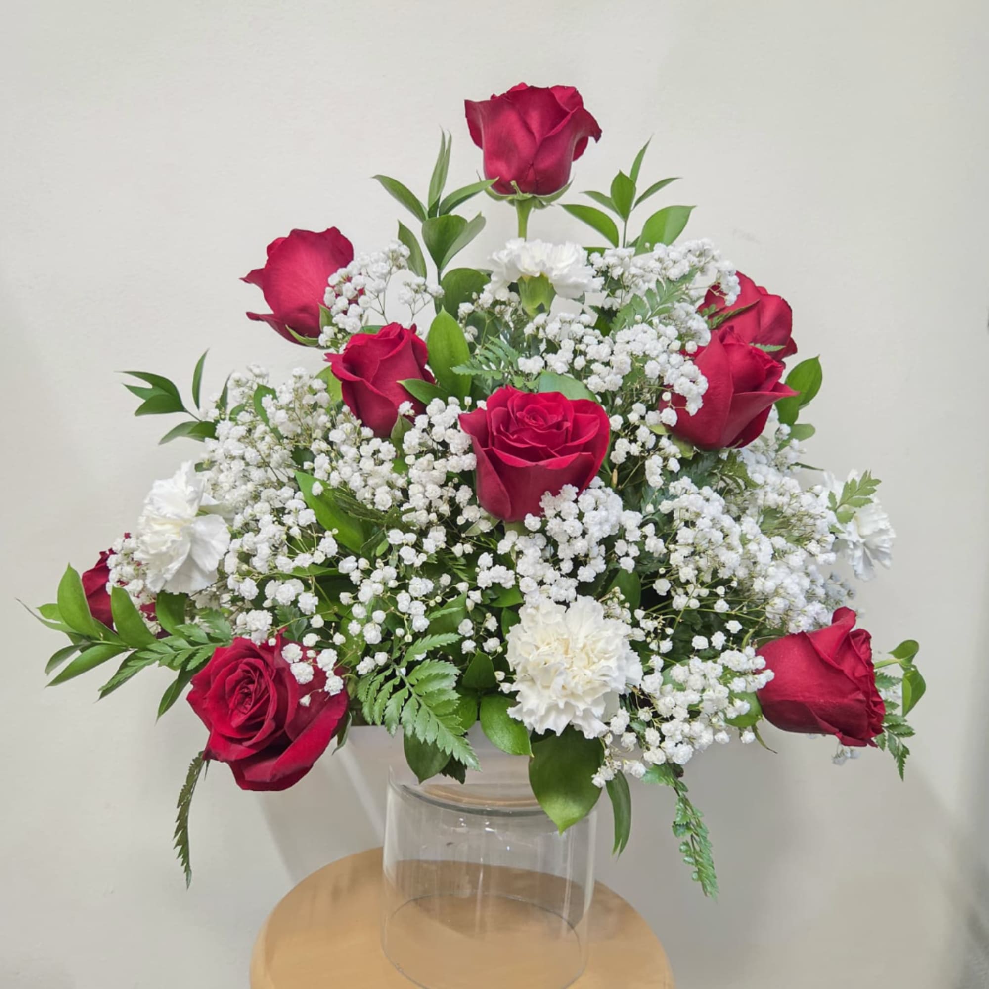 Red roses and white carnations arranged in a clear glass vase