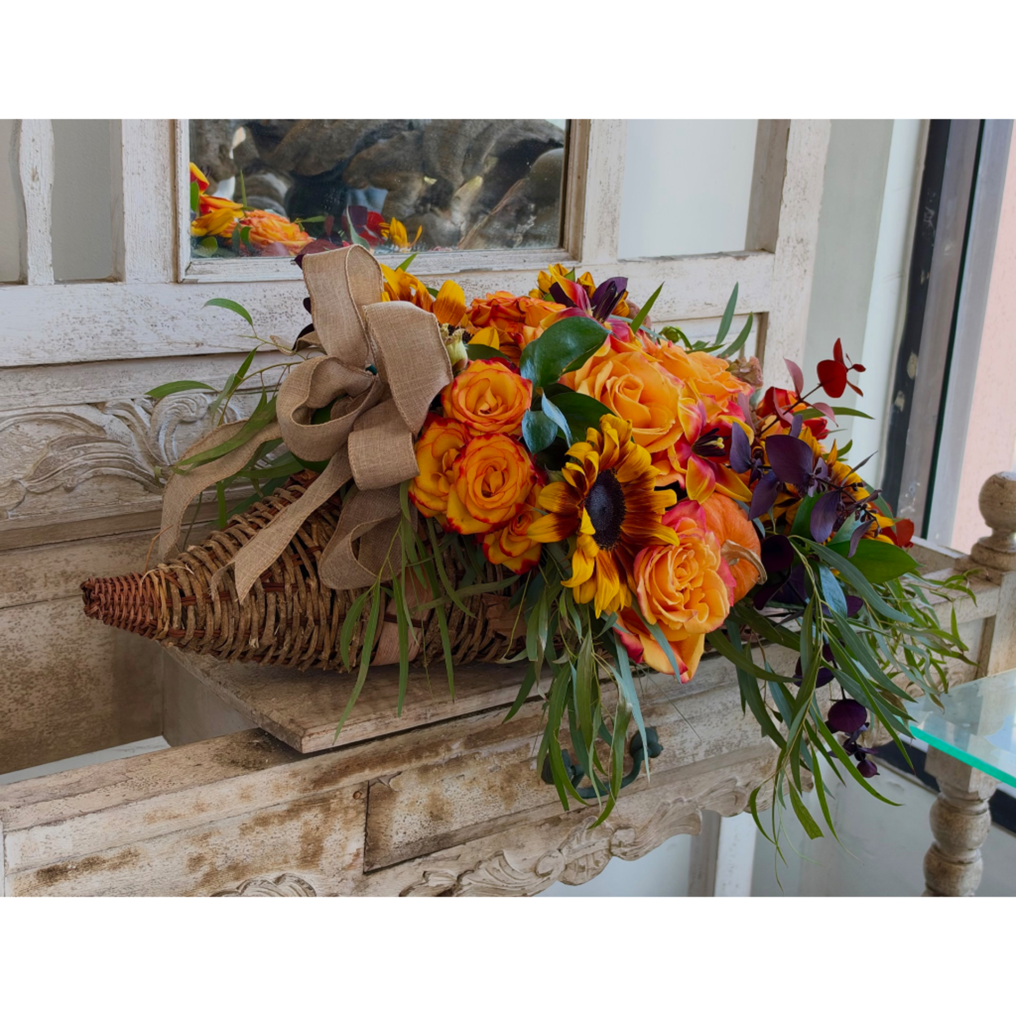 Orange and yellow rose bouquet with sunflowers in a woven basket