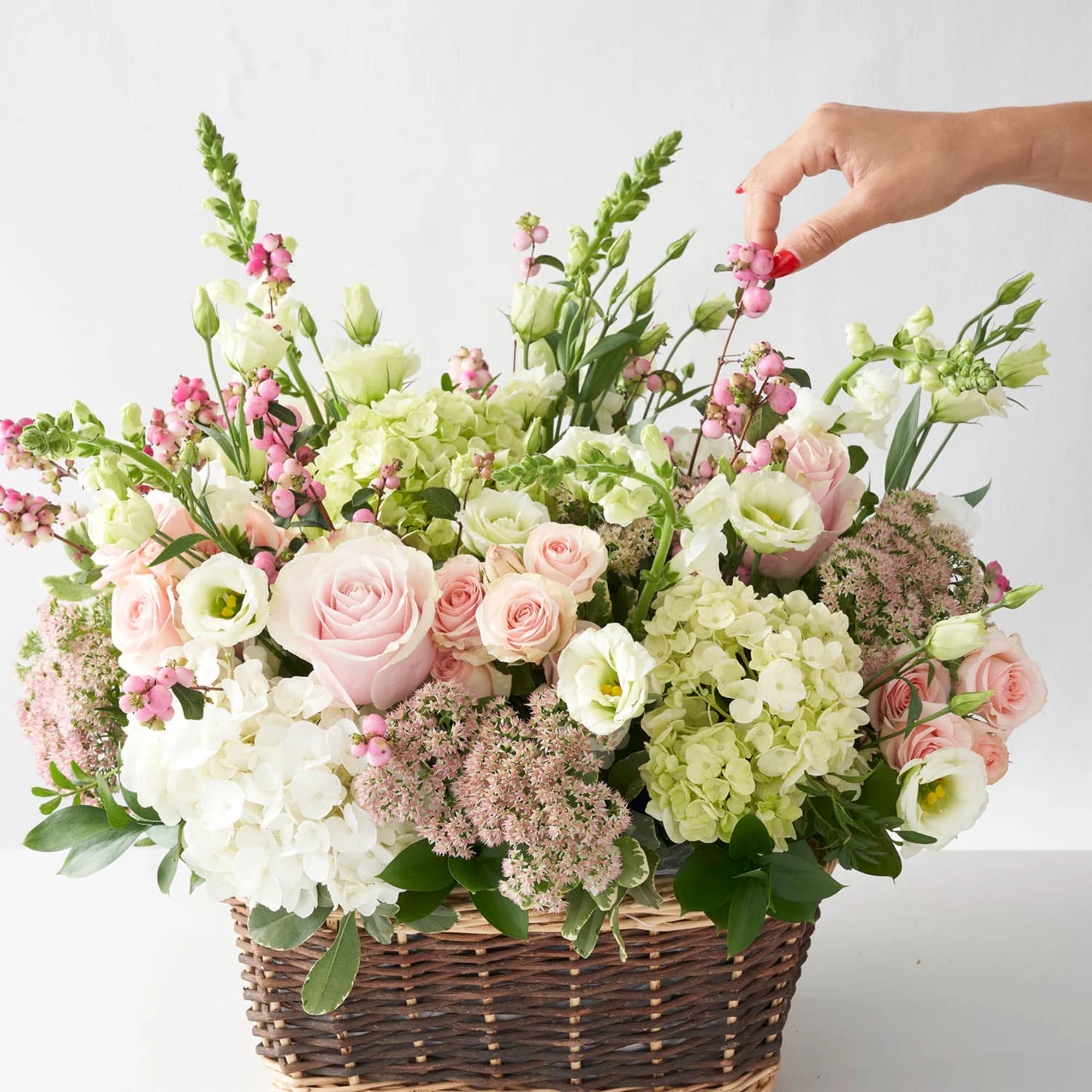 Basket arrangement of pink and white roses with hydrangeas and berries