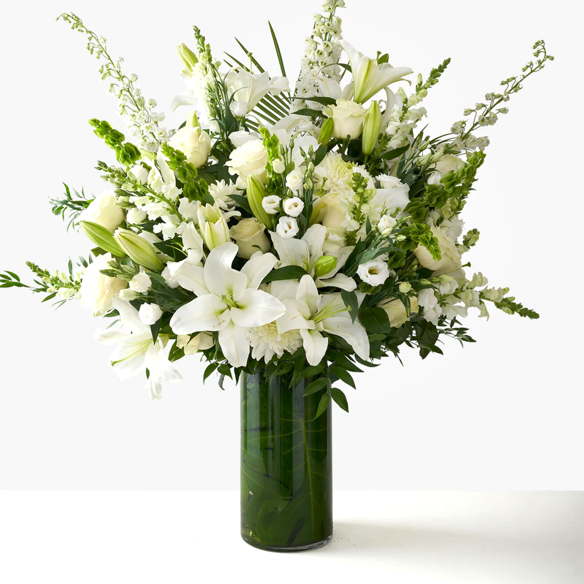 White lilies and roses arranged in a tall glass vase