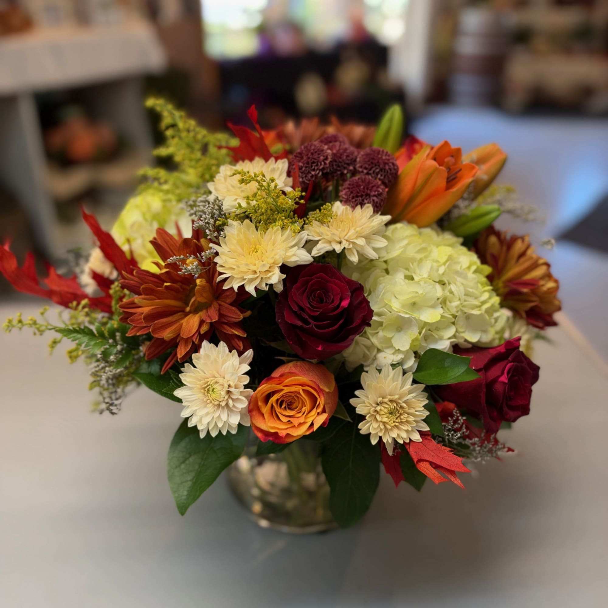Mixed bouquet of roses, chrysanthemums, and hydrangeas in a glass vase