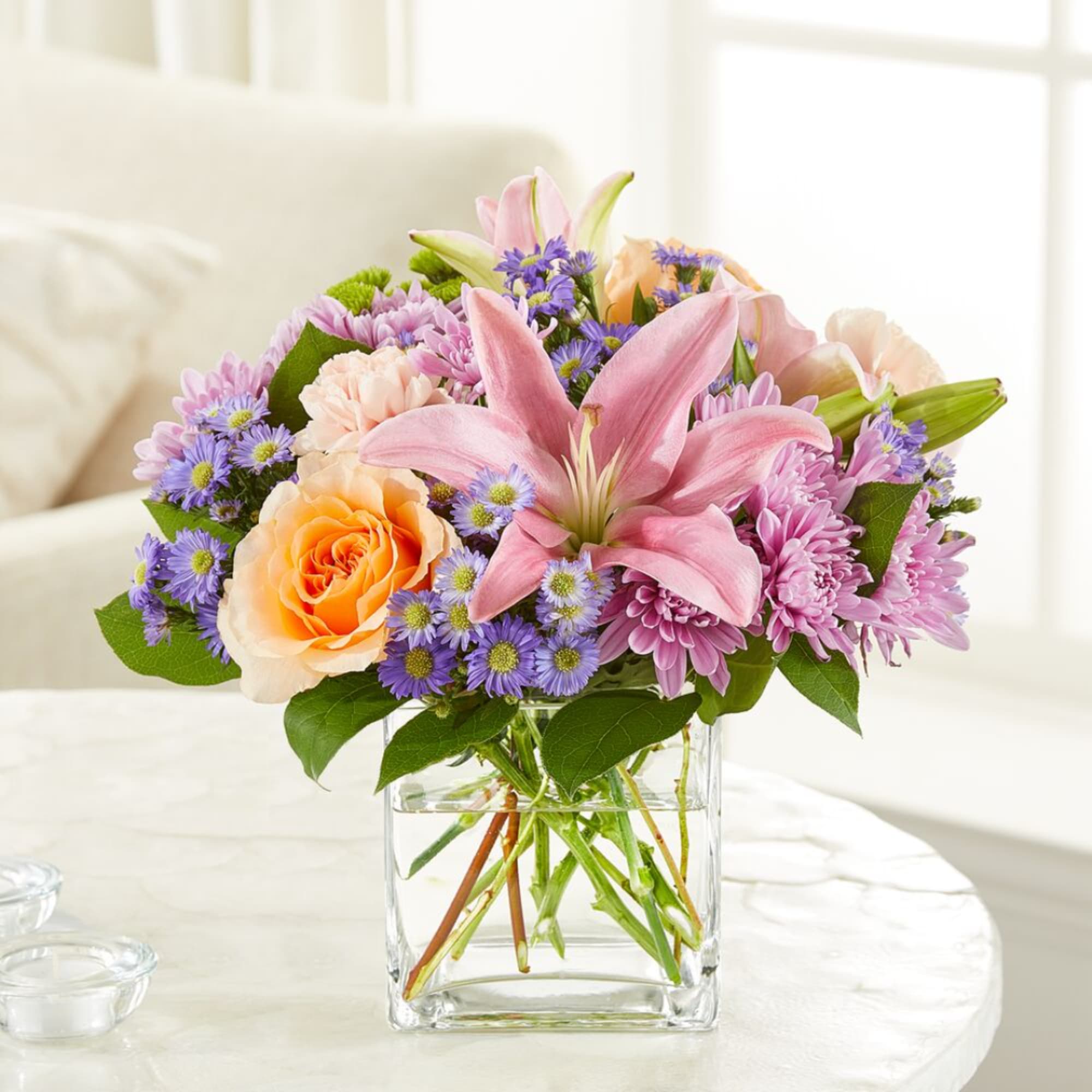 Pink lily and mixed flower bouquet in a clear glass vase