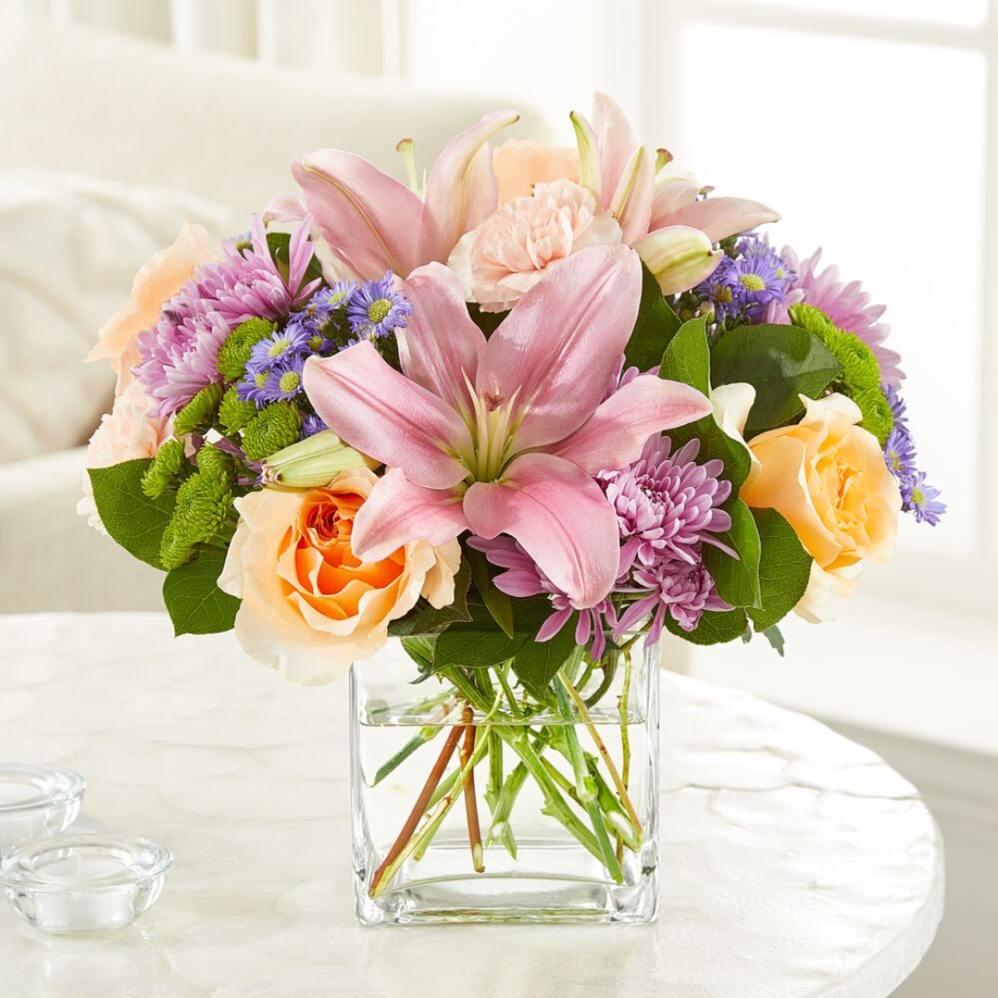 Pink lilies and peach roses in a clear glass vase