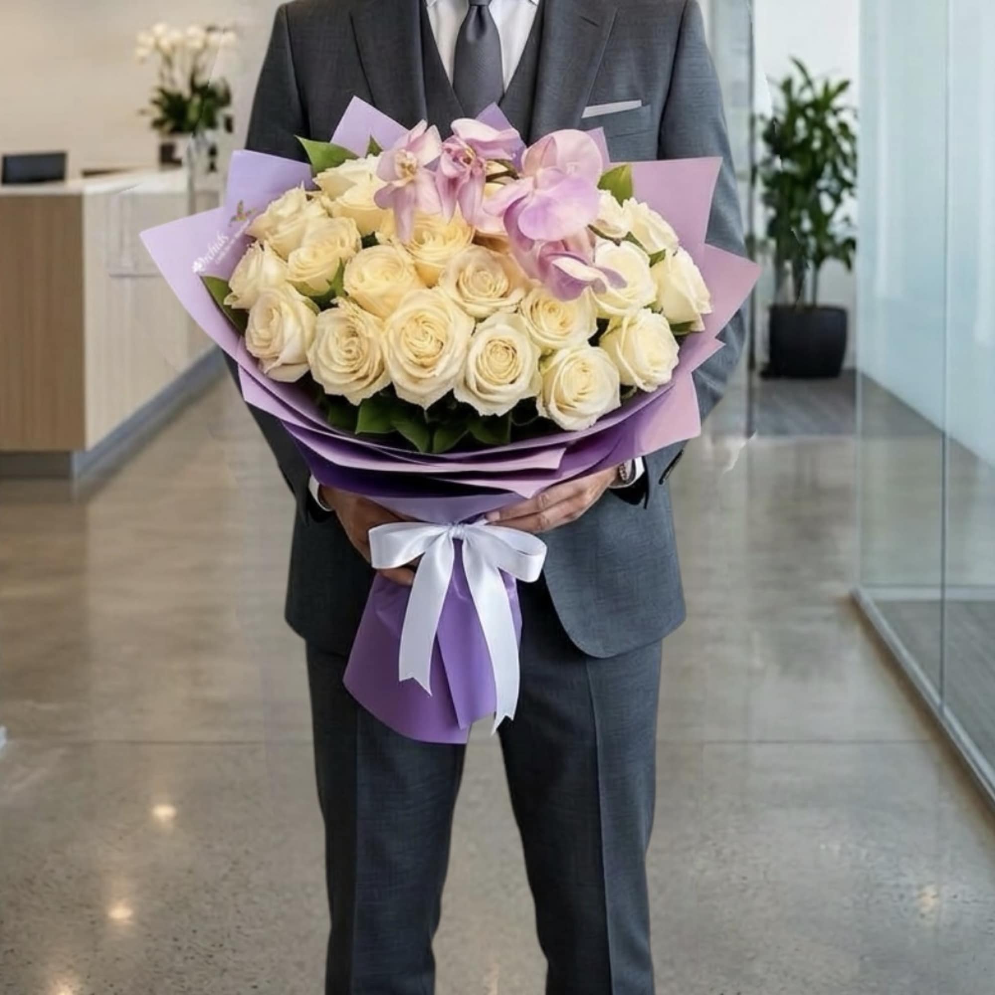 Large bouquet of cream roses and pink orchids wrapped in purple paper